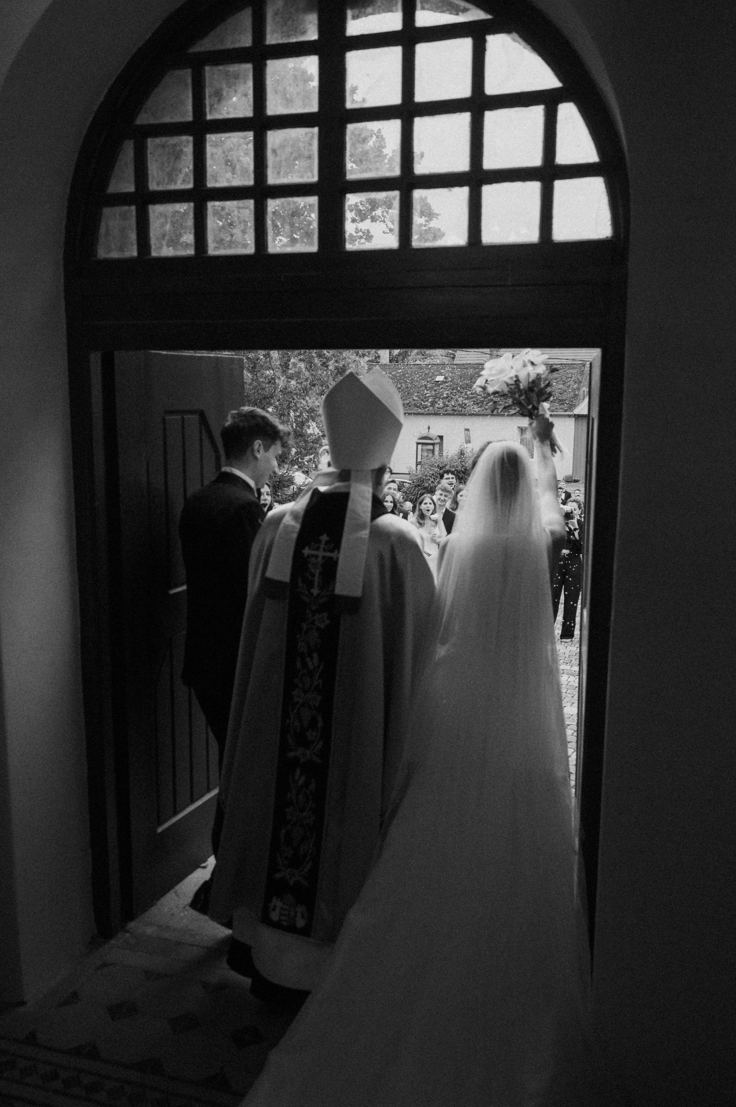 Silhouetted figures stand in dramatic archway with window light streaming through.
