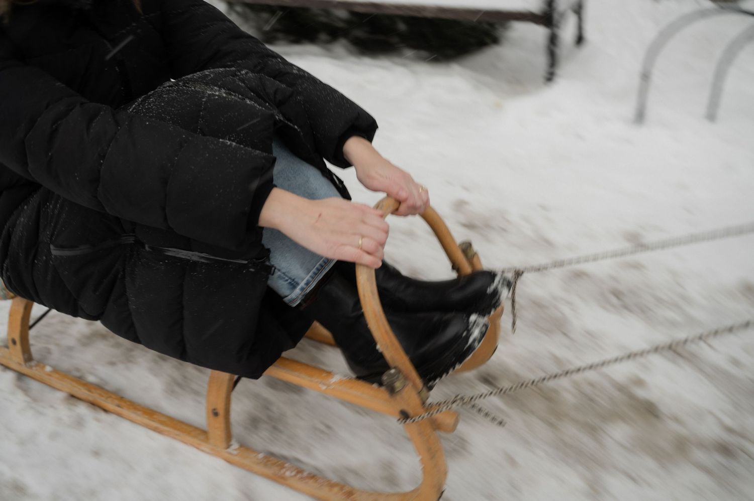 A wooden sled rests in the snow during a winter photoshoot.