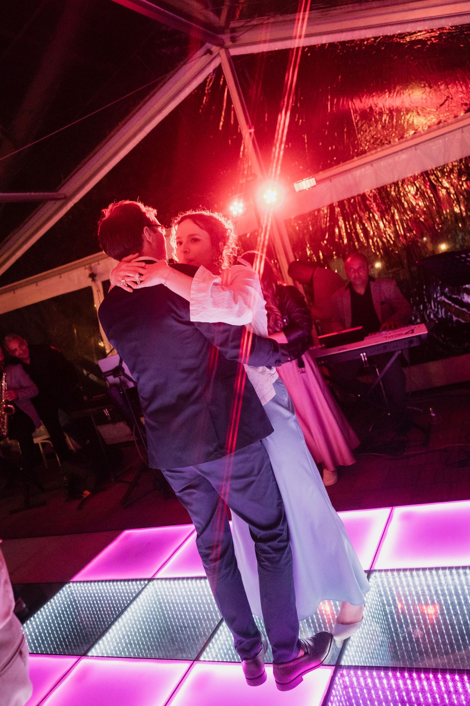 Couple sharing a romantic first dance on a glowing LED dance floor at their wedding reception.