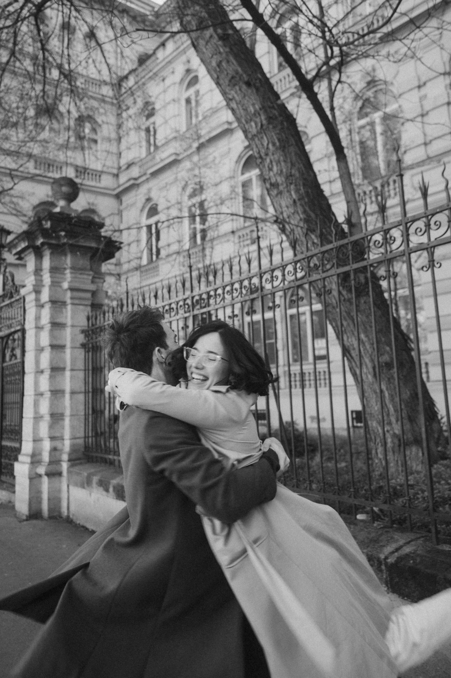 A romantic black and white photo sequence showing a couple embracing near an ornate iron fence and historic building.