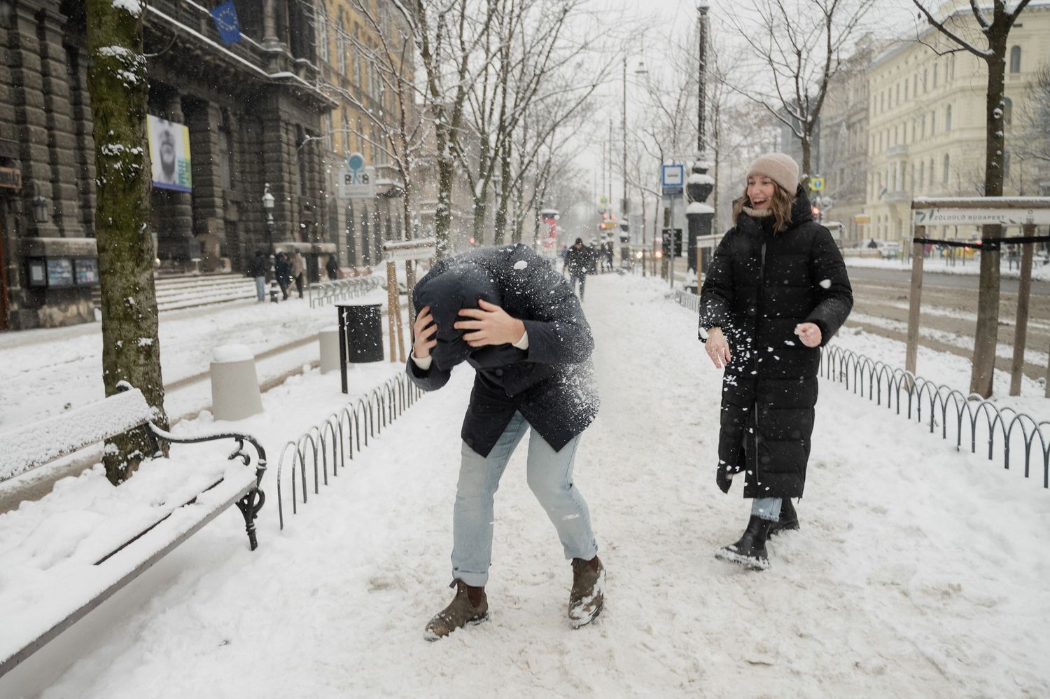 People having fun and playing in the snow on an urban street.