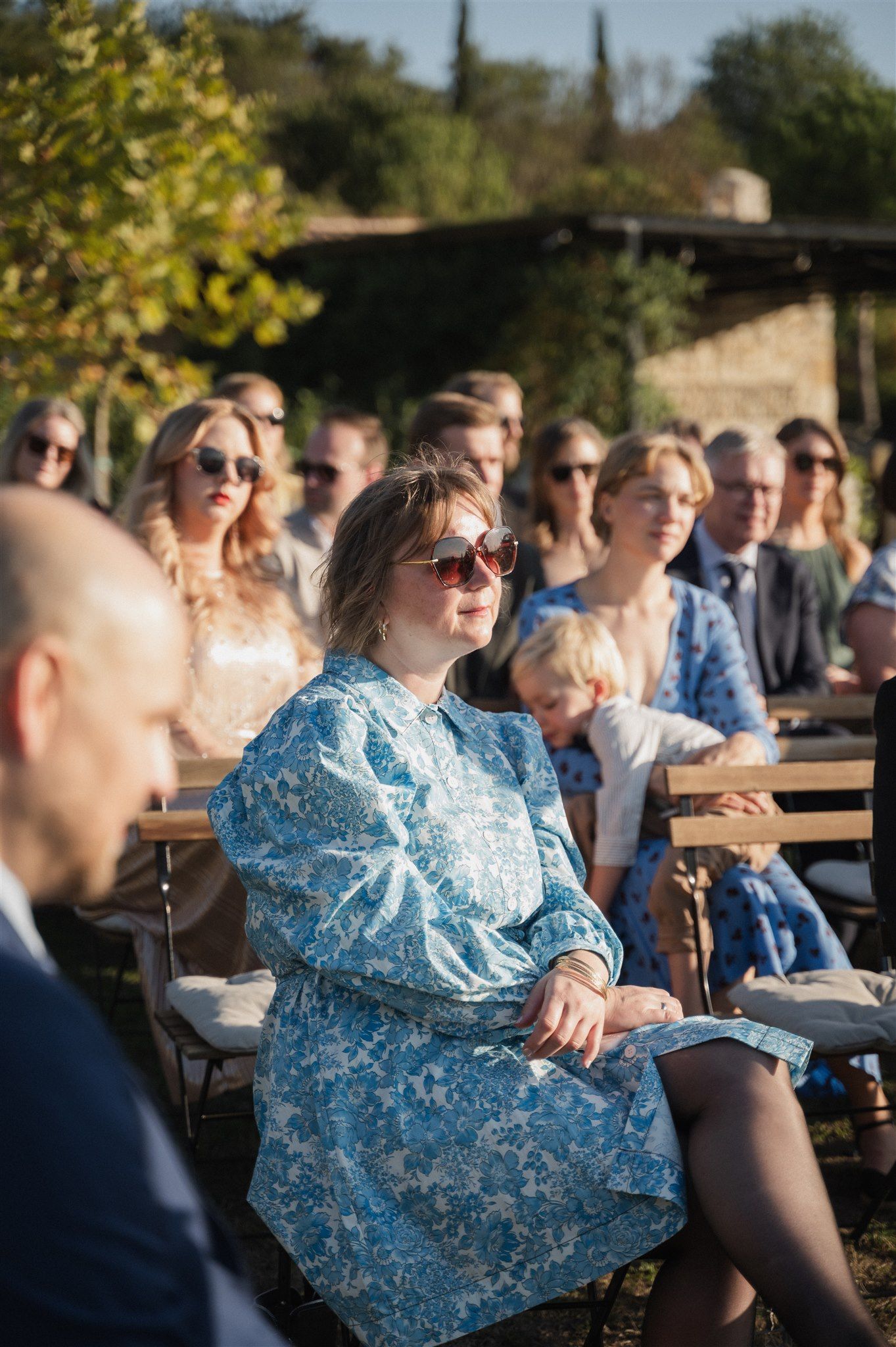 Wedding guests enjoy an outdoor reception on a sunny afternoon.
