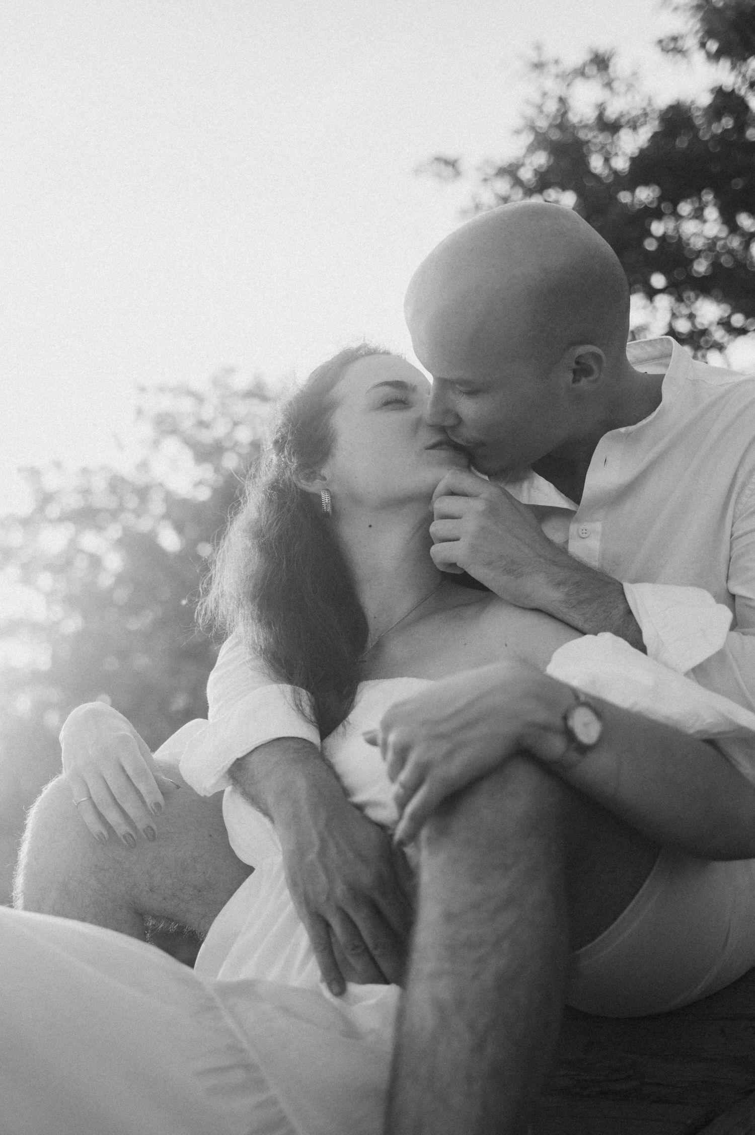 A romantic black and white photo series showing a couple embracing and kissing in soft natural lighting.