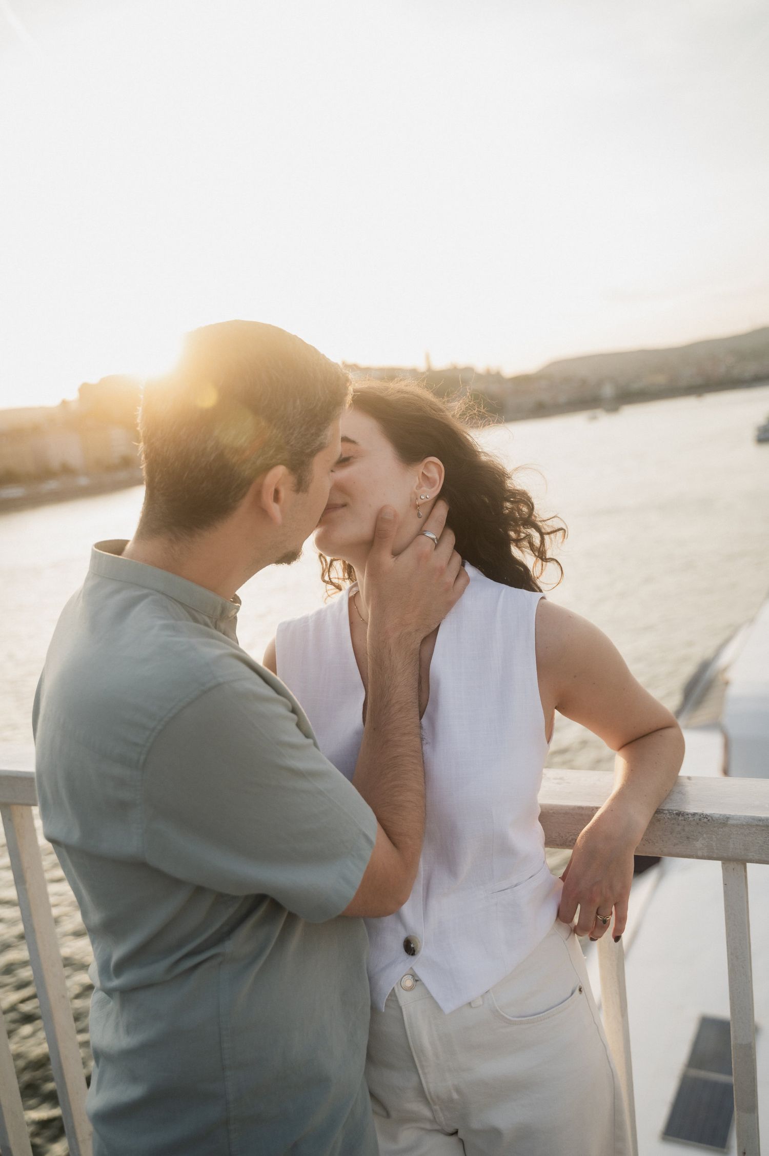 A sunset kiss captured on a waterfront deck with golden hour lighting.