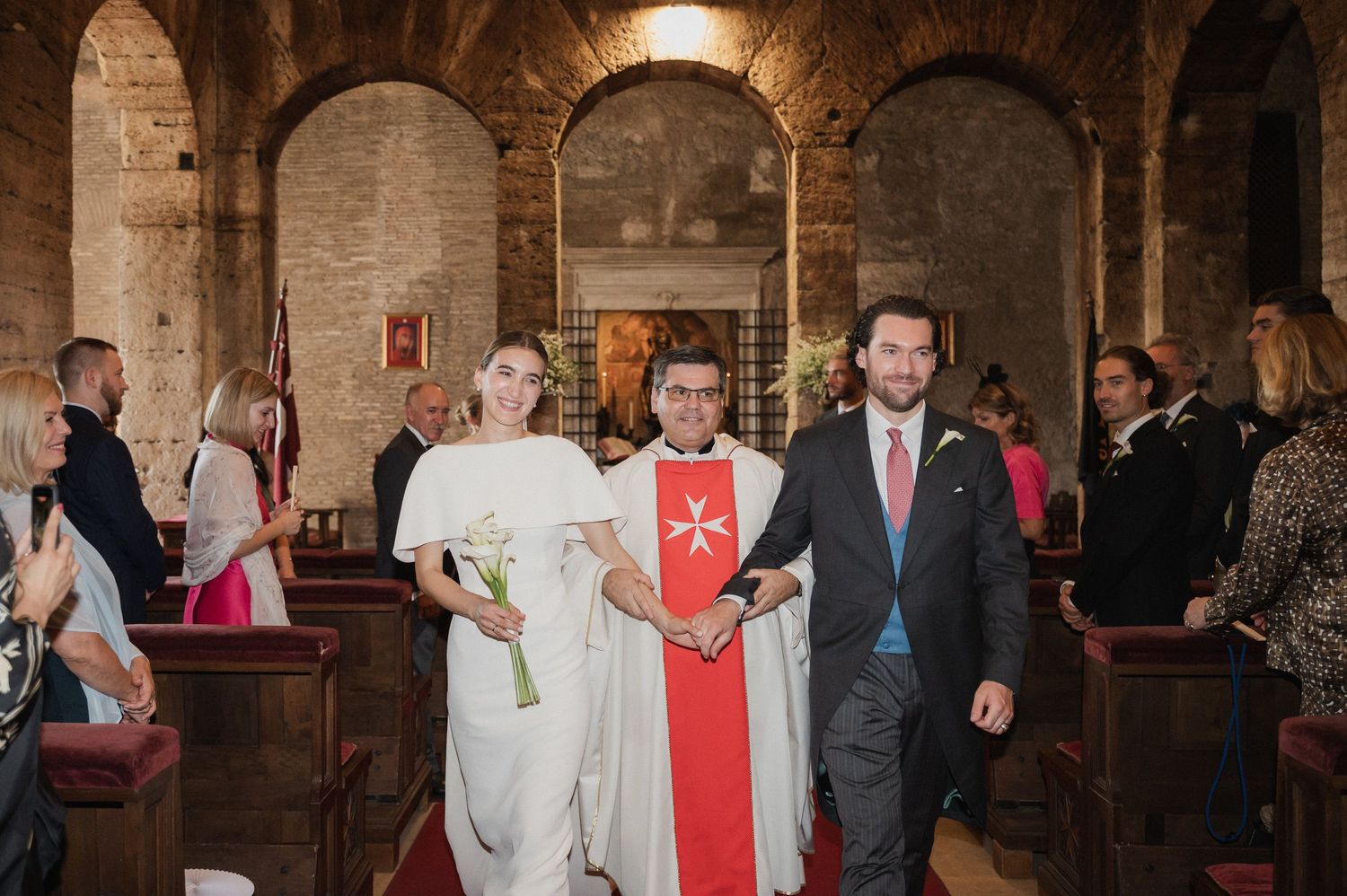 Wedding ceremony processional in stone cathedral with arched ceilings.