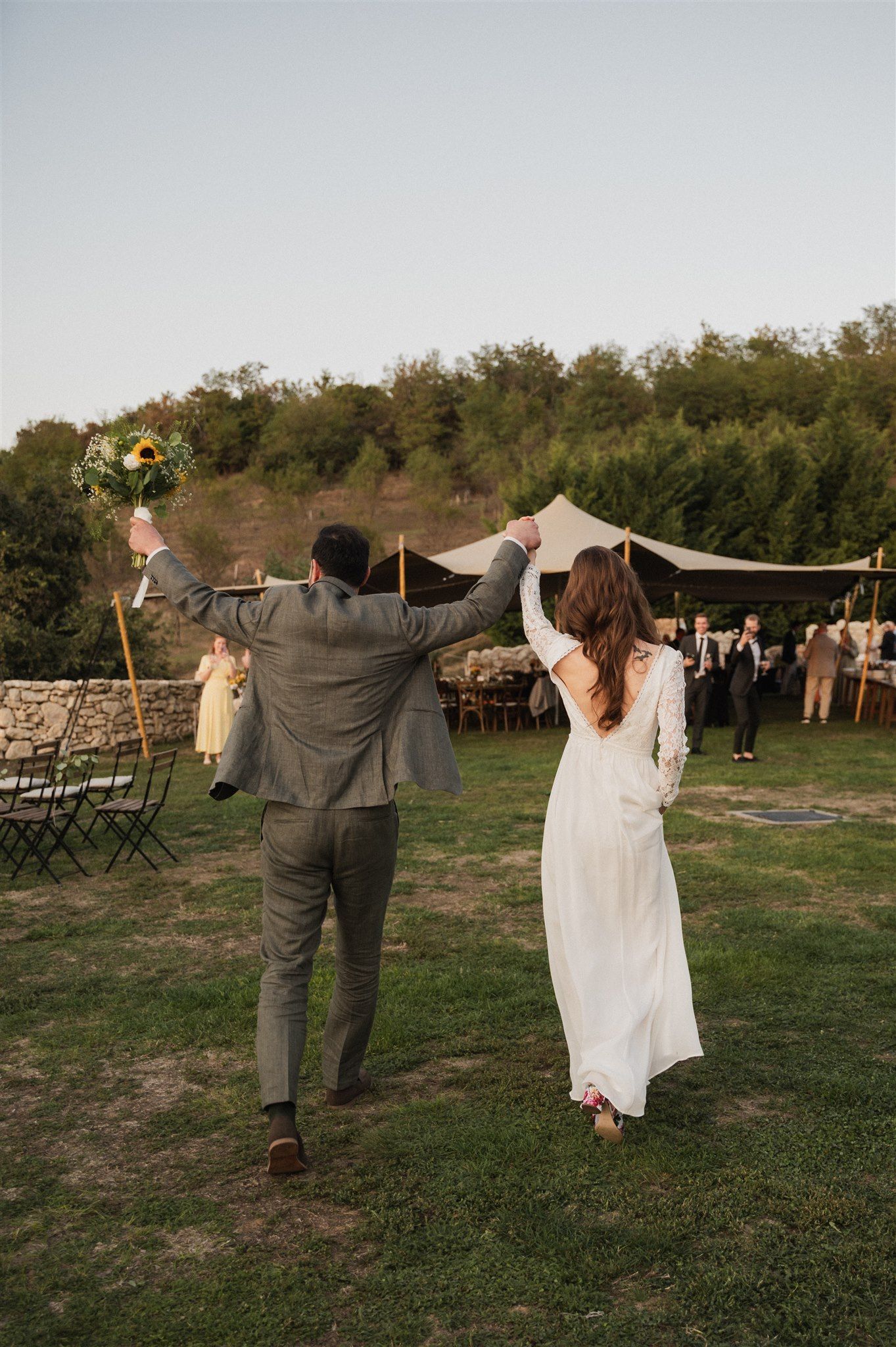 Newlyweds celebrating with arms raised in victory pose on their wedding day.