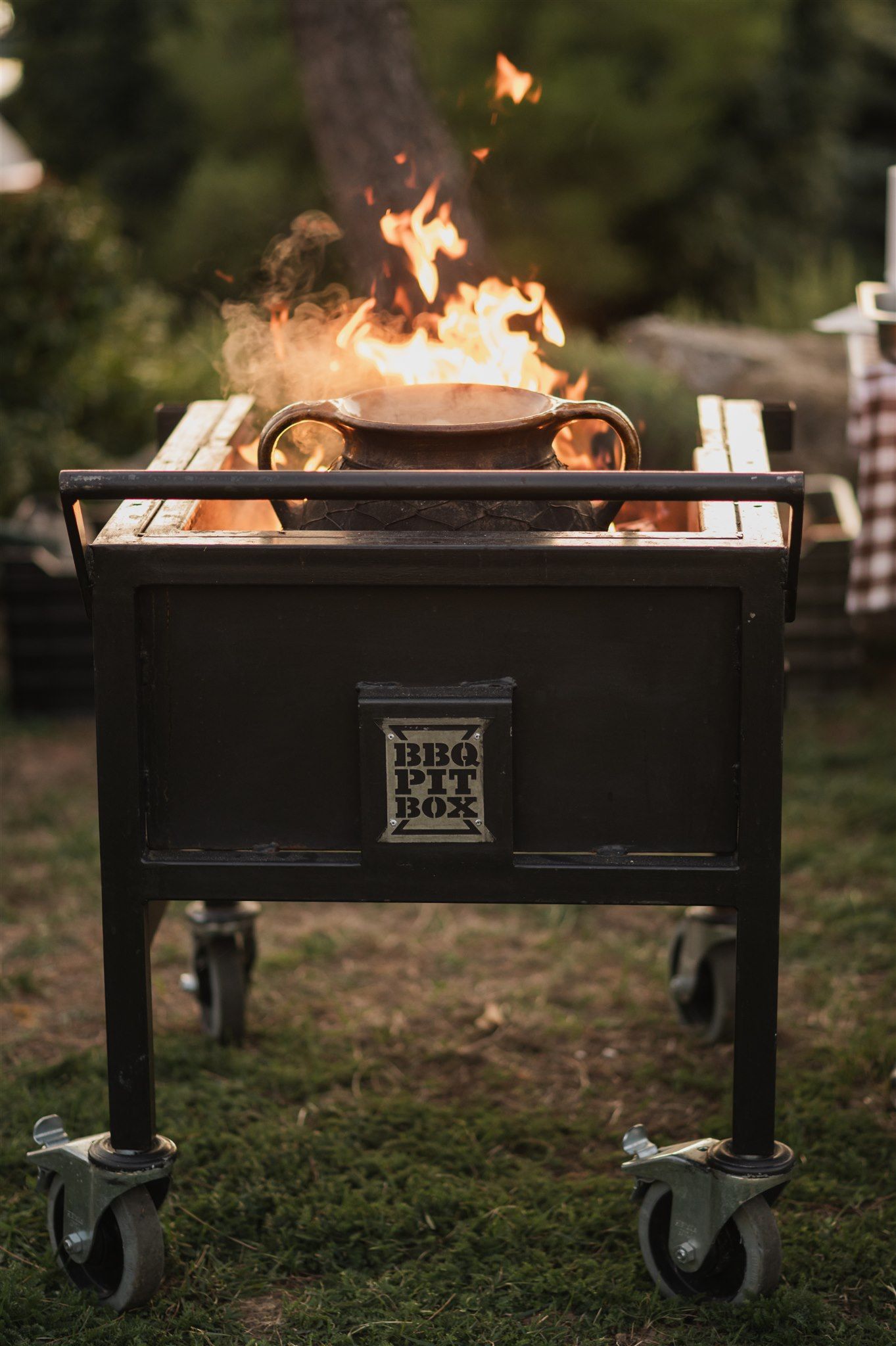 Black metal fire pit with flames burning during outdoor evening event.