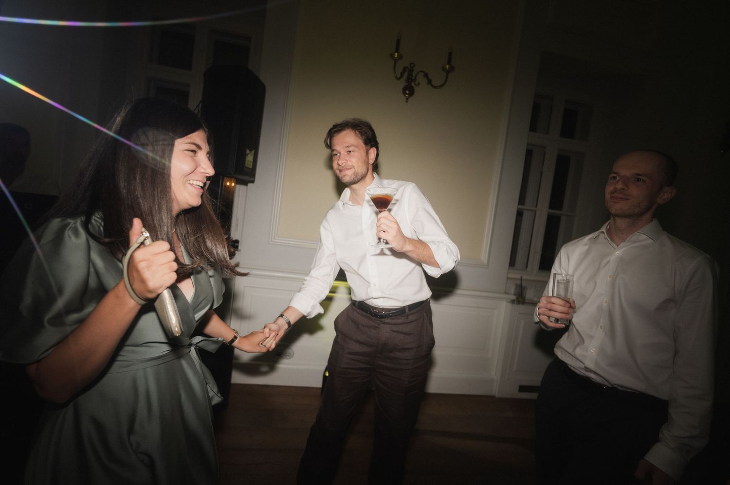 Guests dancing and celebrating at an indoor wedding reception party at night.