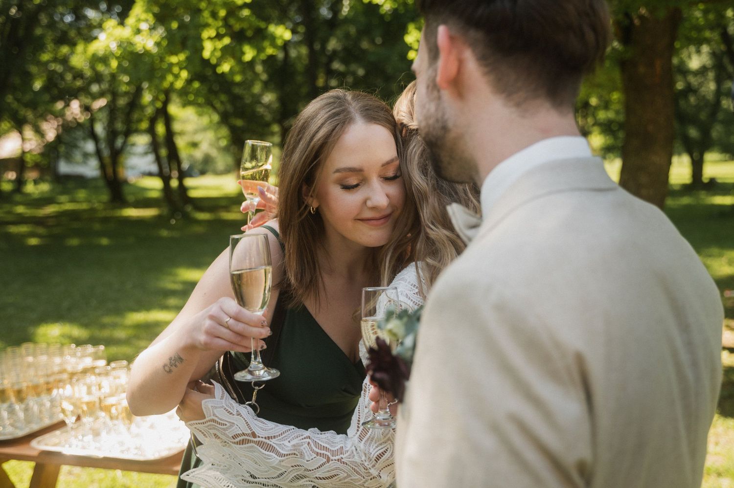 A romantic outdoor wedding celebration with guests toasting champagne in a sunlit garden setting.