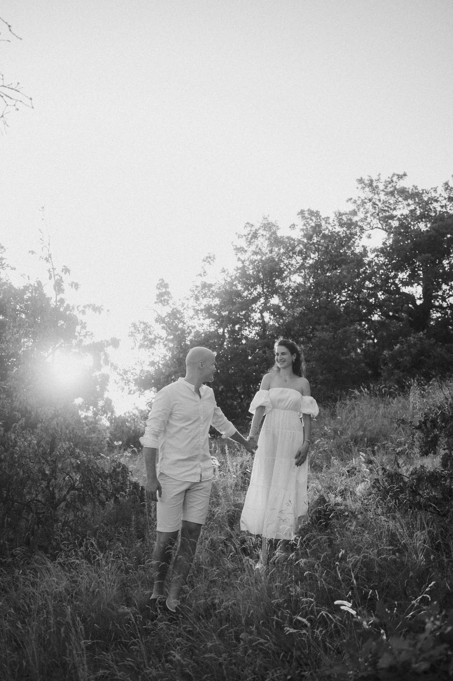 A family walks together through a misty field at sunset creating a dreamy black and white silhouette.