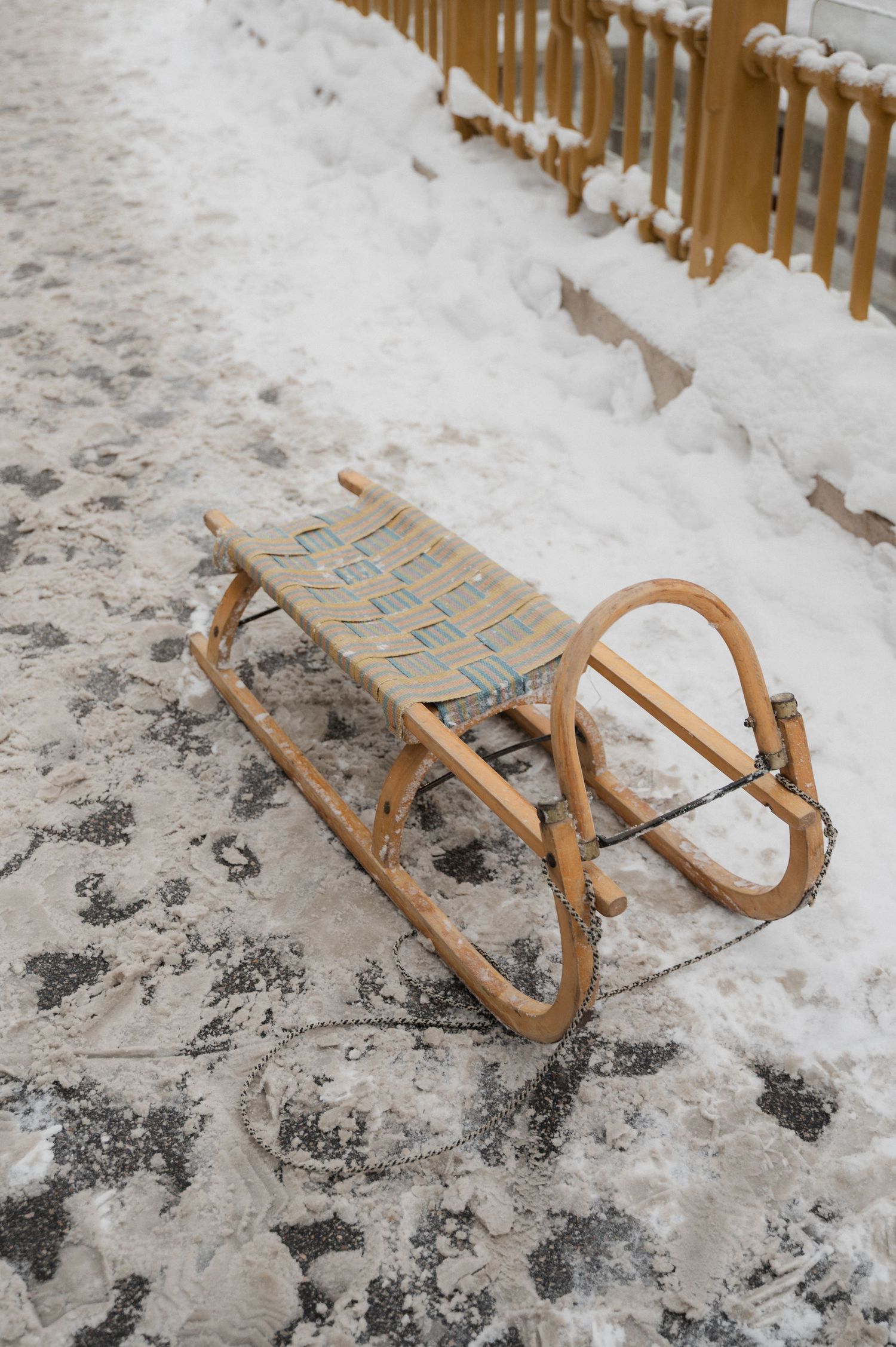 A vintage wooden sled with curved runners lying in the snow.