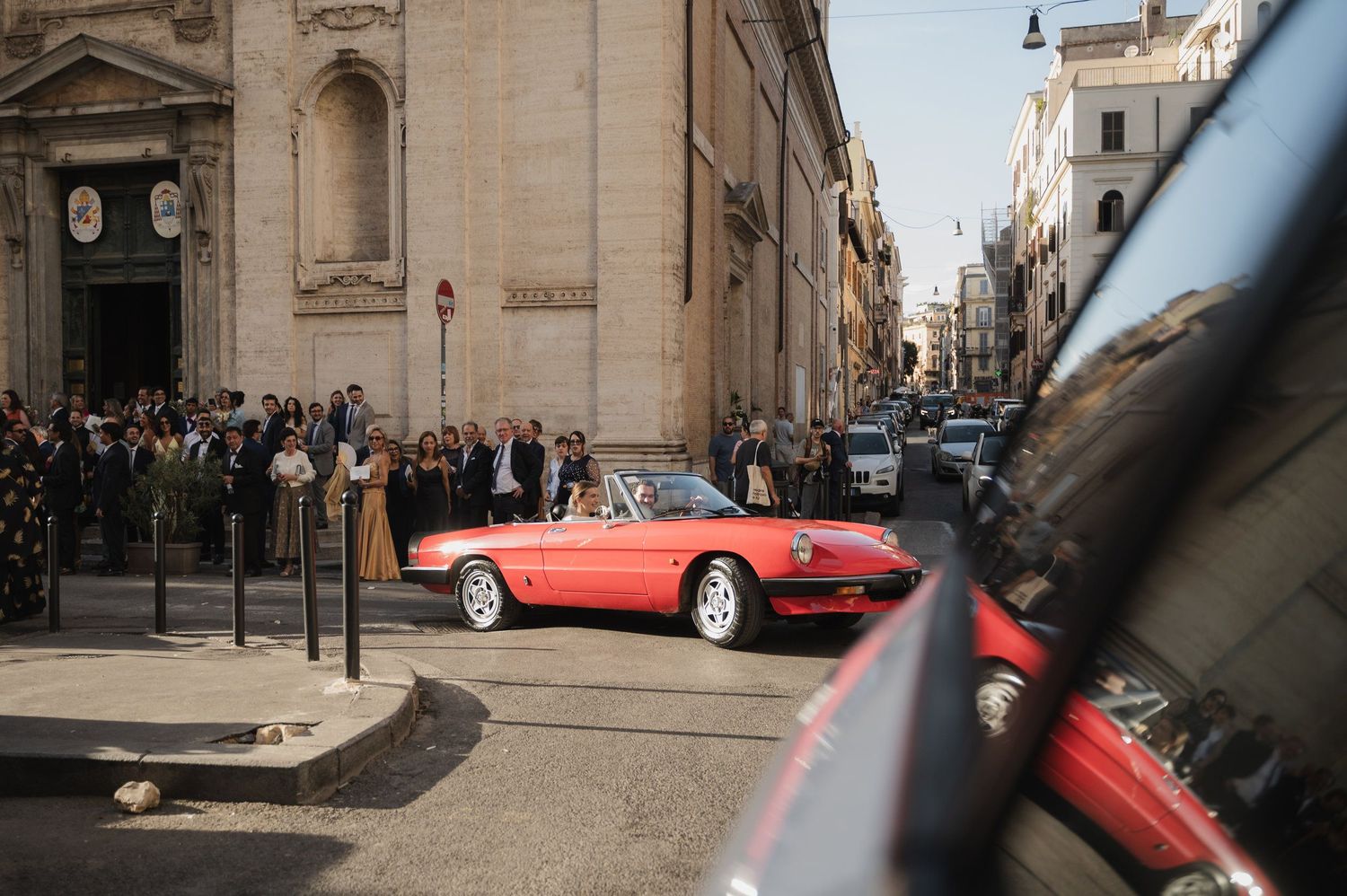 Classic red vintage sports car parked on a charming European cobblestone street.