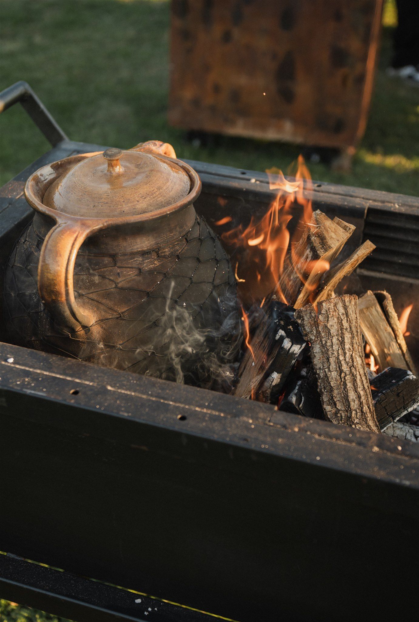 Cast iron pan cooking over open flames on outdoor grill.