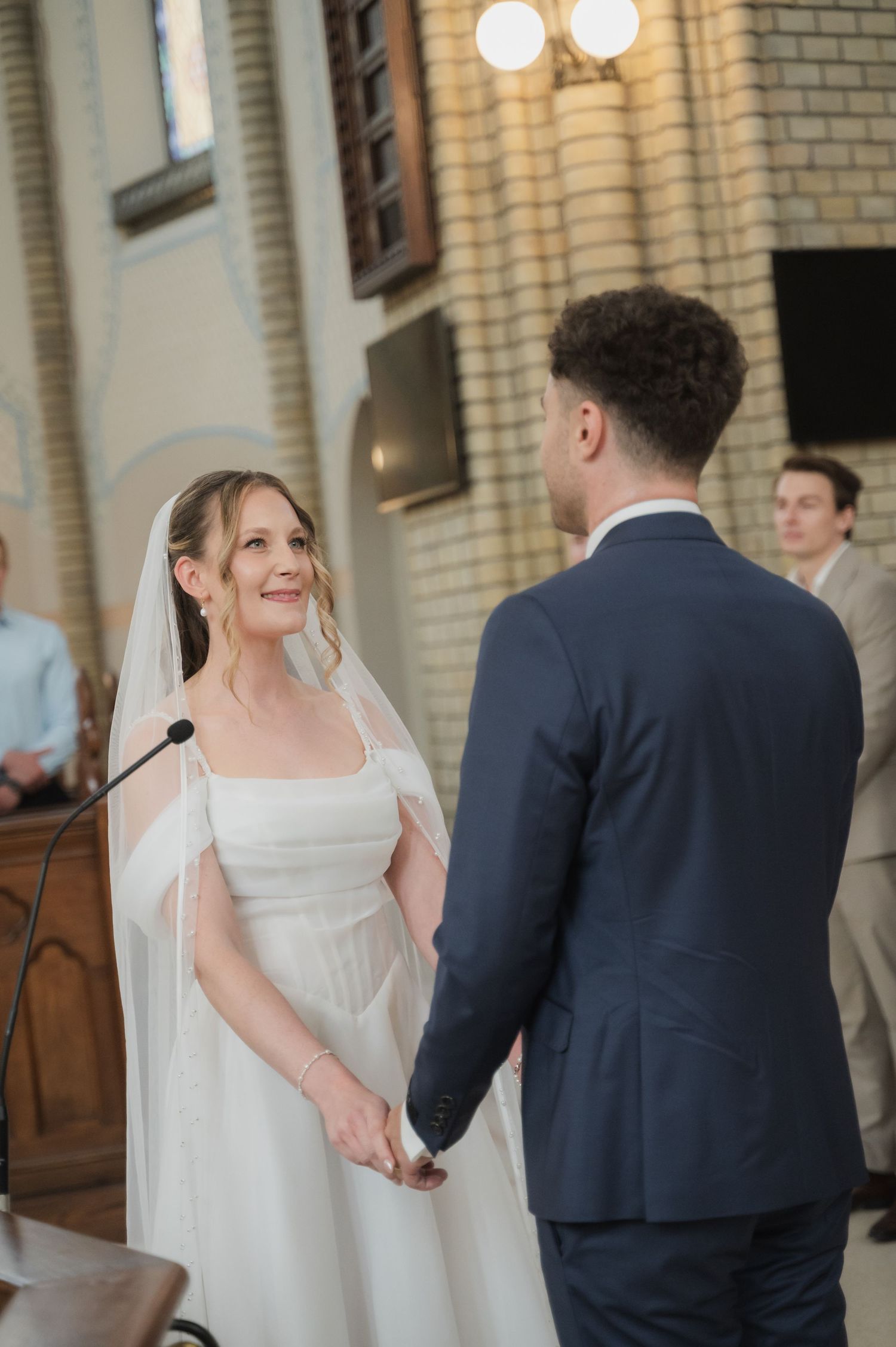 Bride and groom holding hands at church wedding ceremony altar, smiling joyfully.