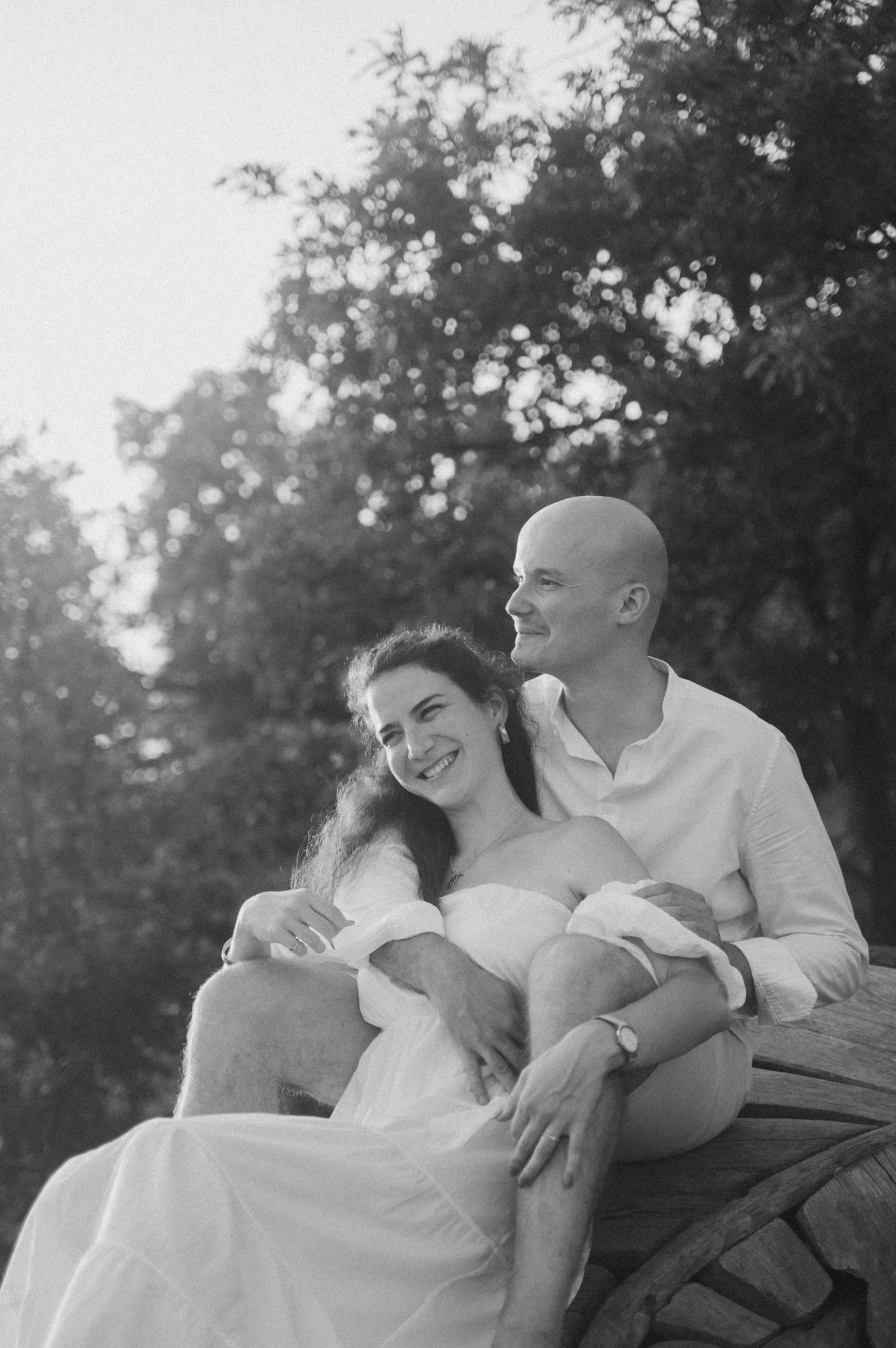 A romantic black and white photo sequence shows a couple sharing tender moments while sitting together outdoors.