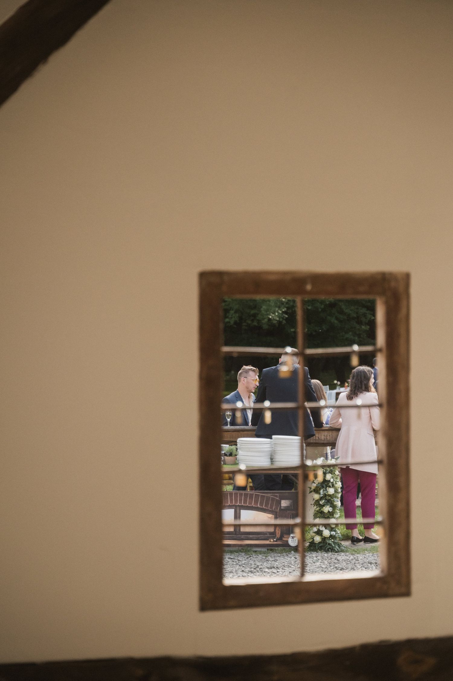 A series of rustic wooden window frames mounted on a beige wall show glimpses of an outdoor scene.
