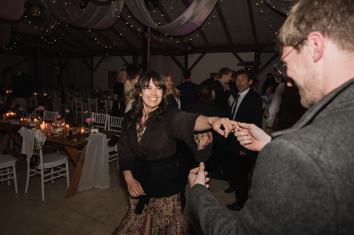 People dancing and socializing at a dimly lit indoor event with festive lighting and decorations.