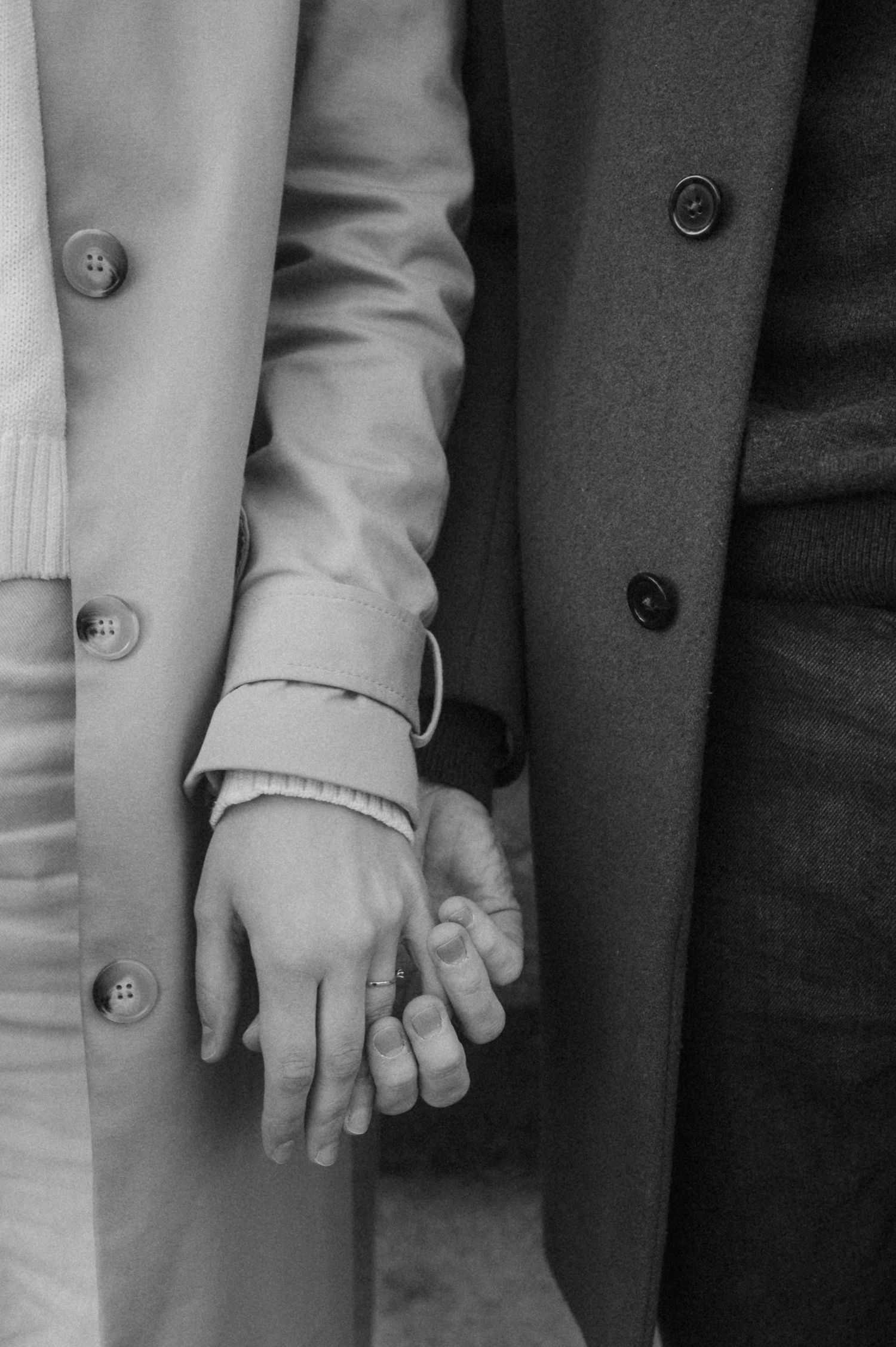 Black and white photo showing a row of hands holding each other in unity, with suit sleeves visible in the background.
