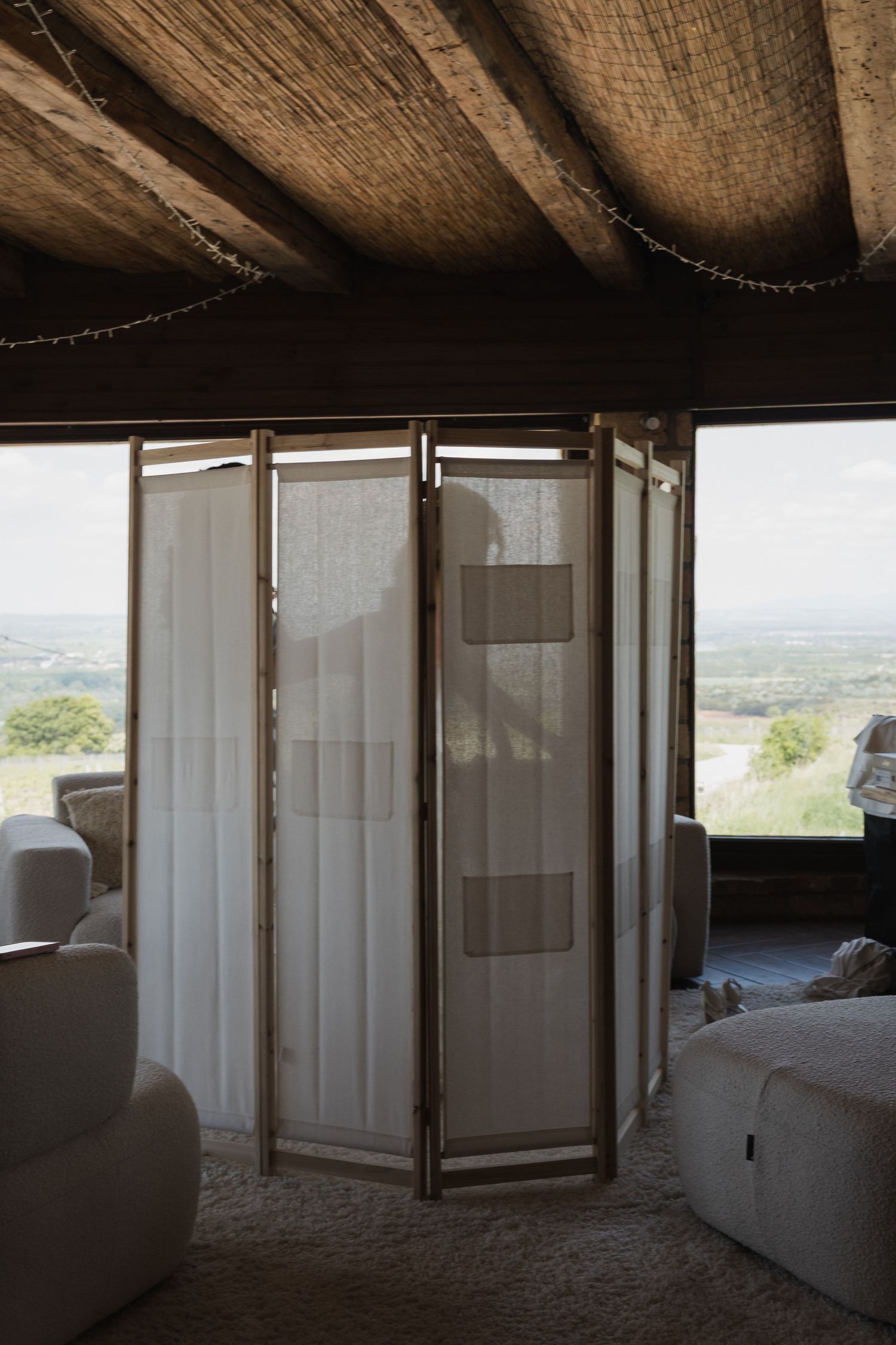 A folding room divider screen in a rustic venue with wooden beam ceiling and scenic countryside views.