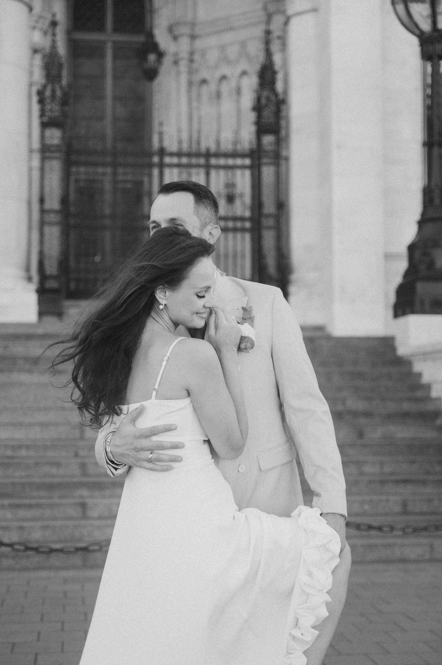 A black and white photo captures an intimate embrace between newlyweds.