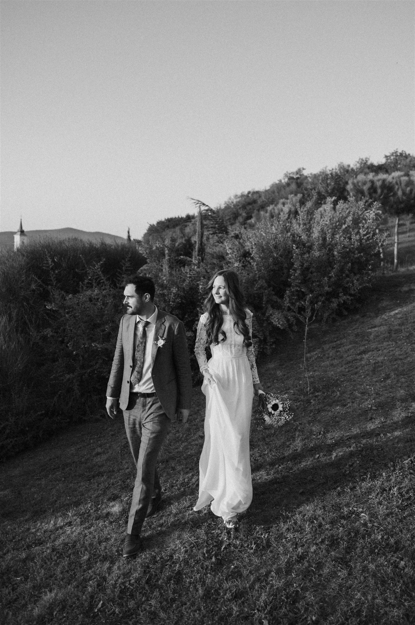 Black and white photo of a couple walking along a hillside path together.