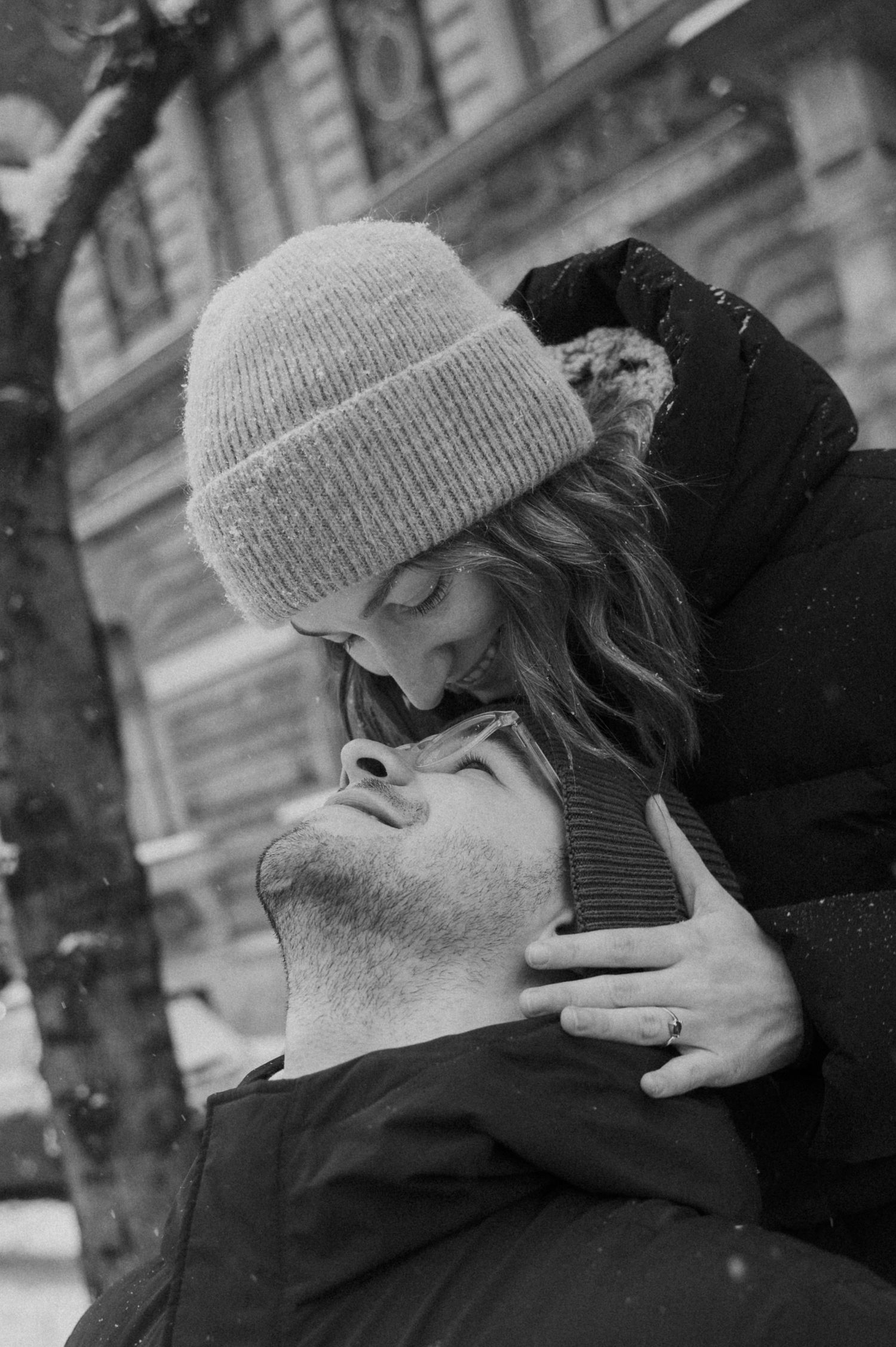 A tender moment captured between two people wearing winter hats in black and white.