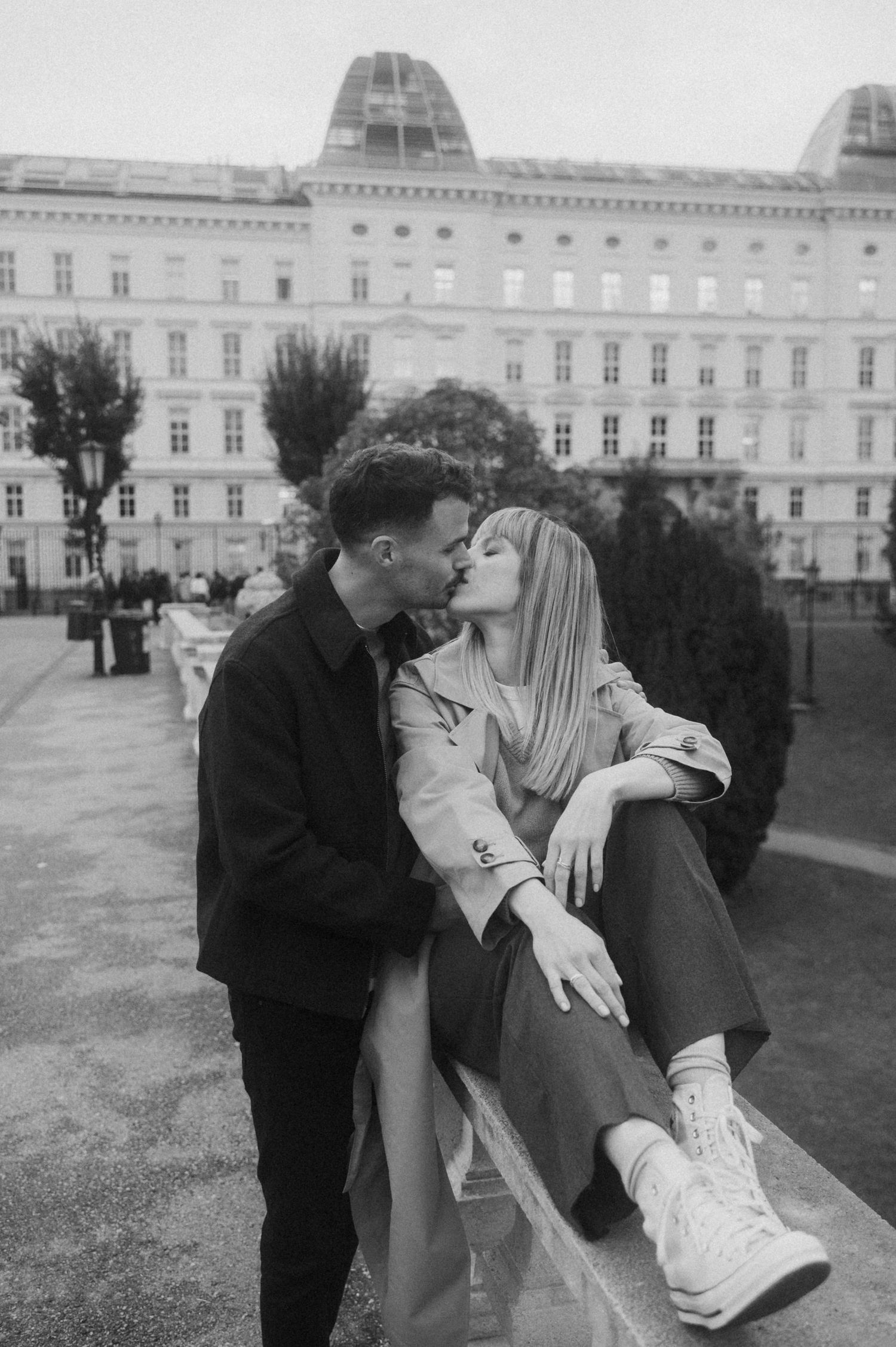A romantic couple shares tender moments in a sequence of black and white photos on palace grounds.