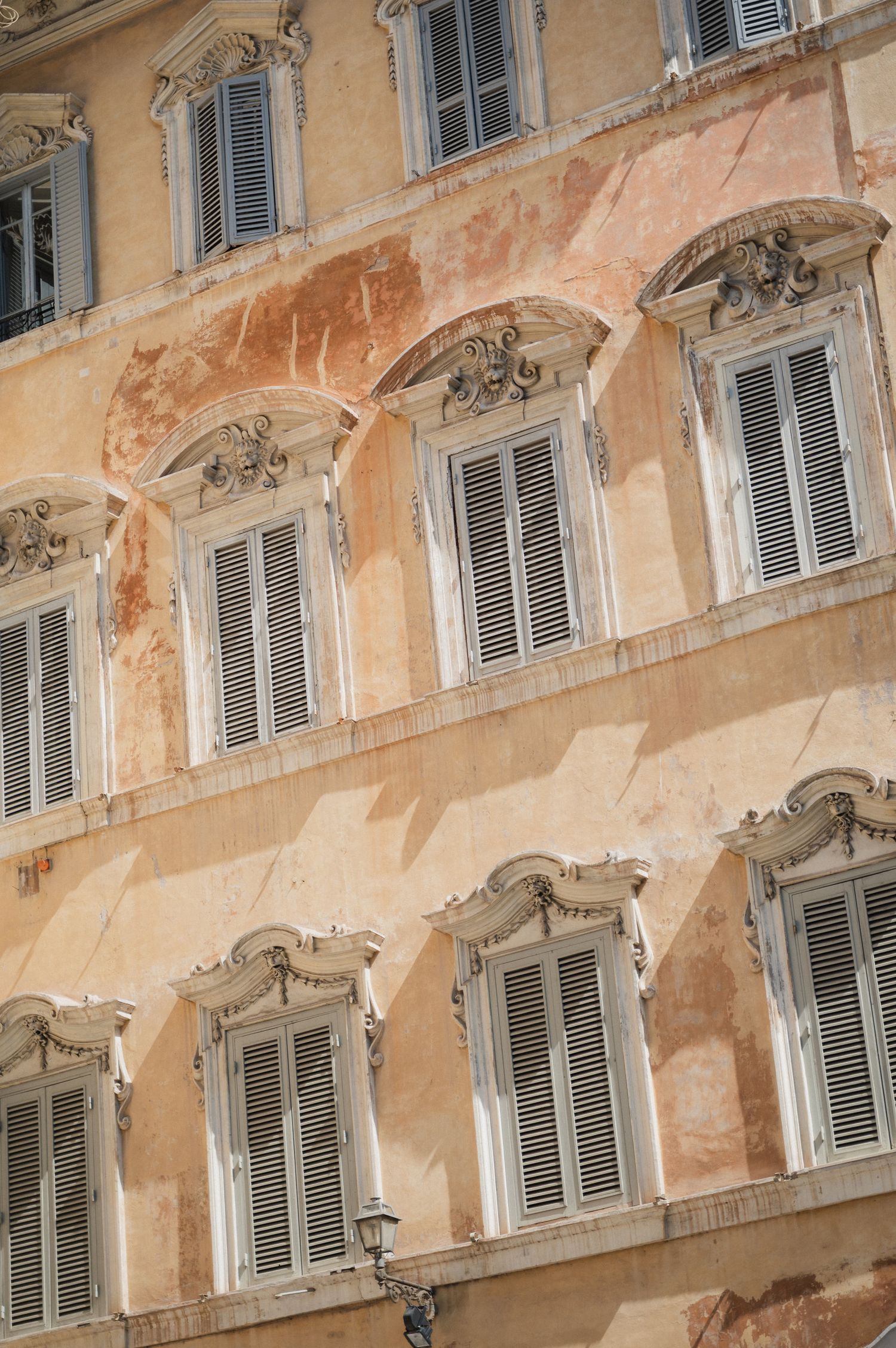Architectural detail of vintage building facade with rows of shuttered windows and ornate decorations.