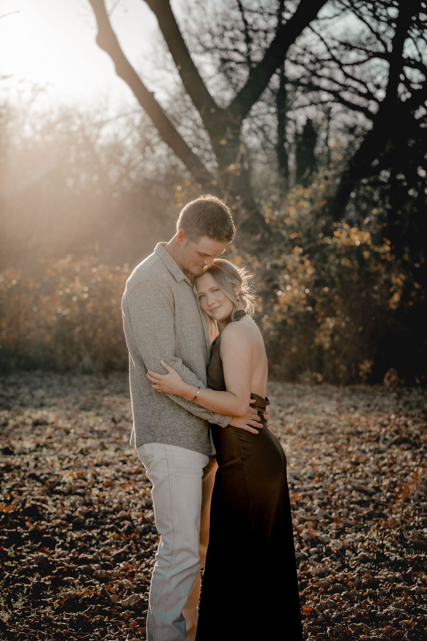 A couple shares an intimate moment in a sunlit autumn forest.