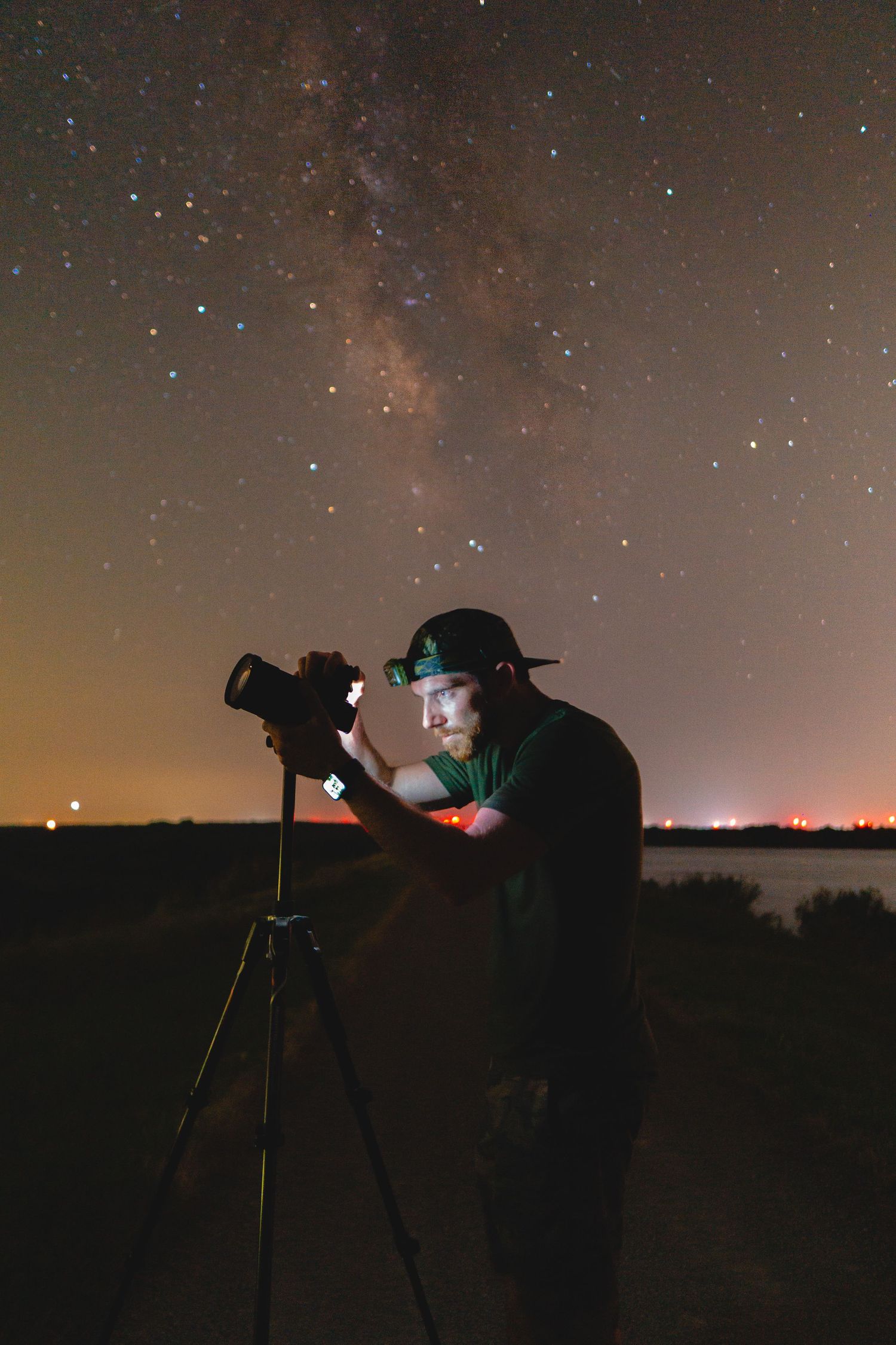 Silhouettes of photographers capturing night sky and stars with tripod-mounted cameras.