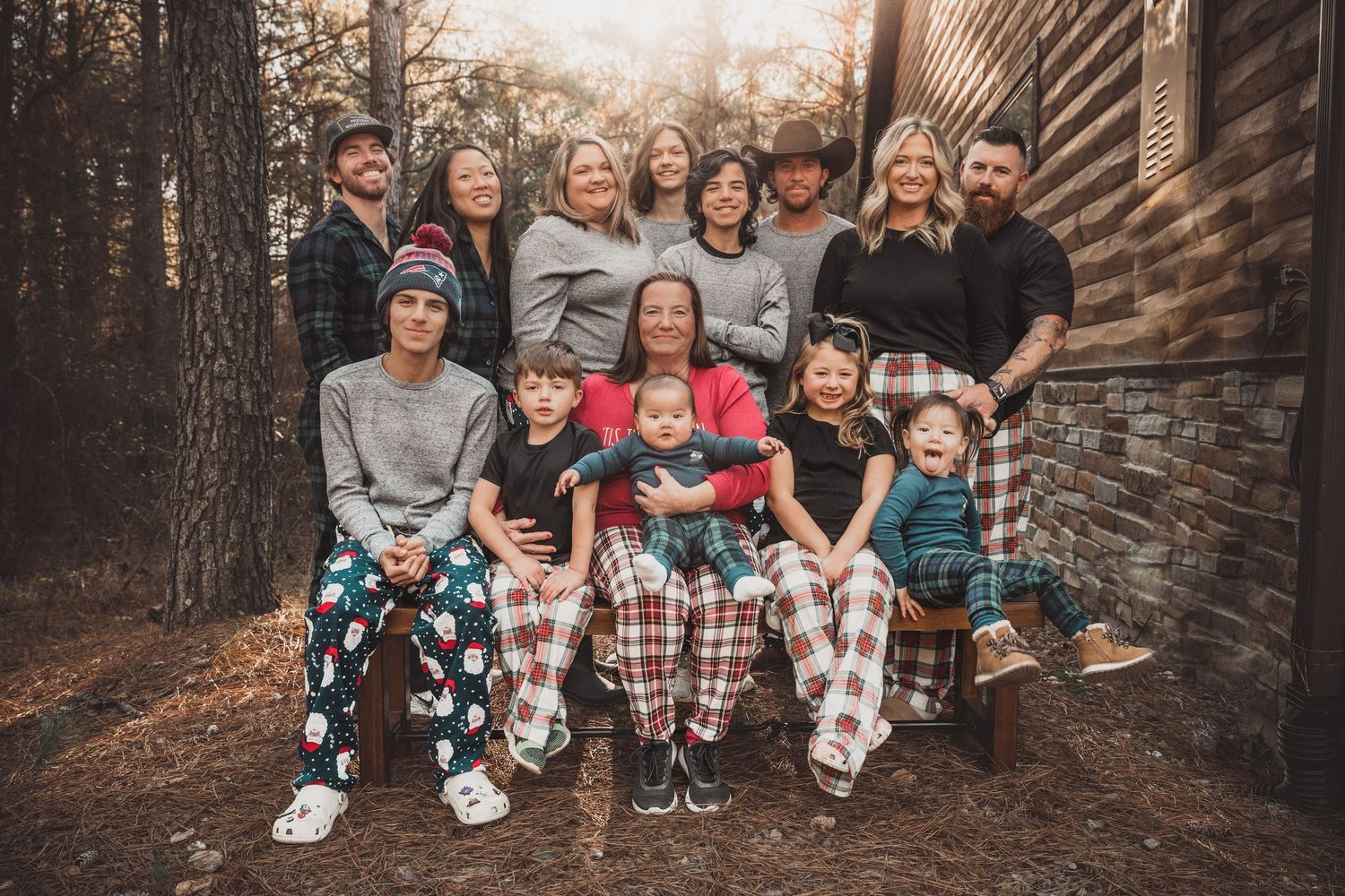 Extended family gathering for a casual outdoor photo session near a stone building.