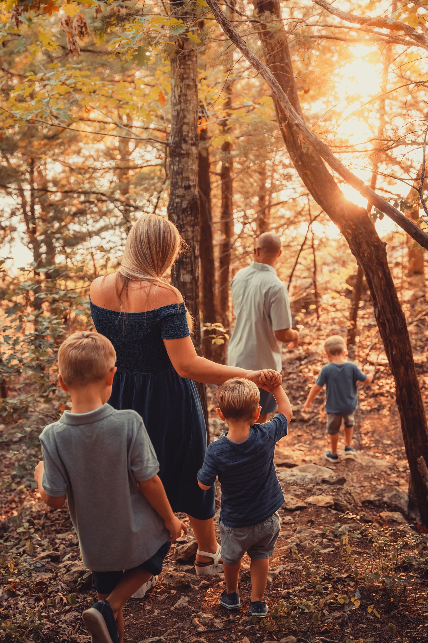 Family walking together through sunlit autumn forest on nature trail.