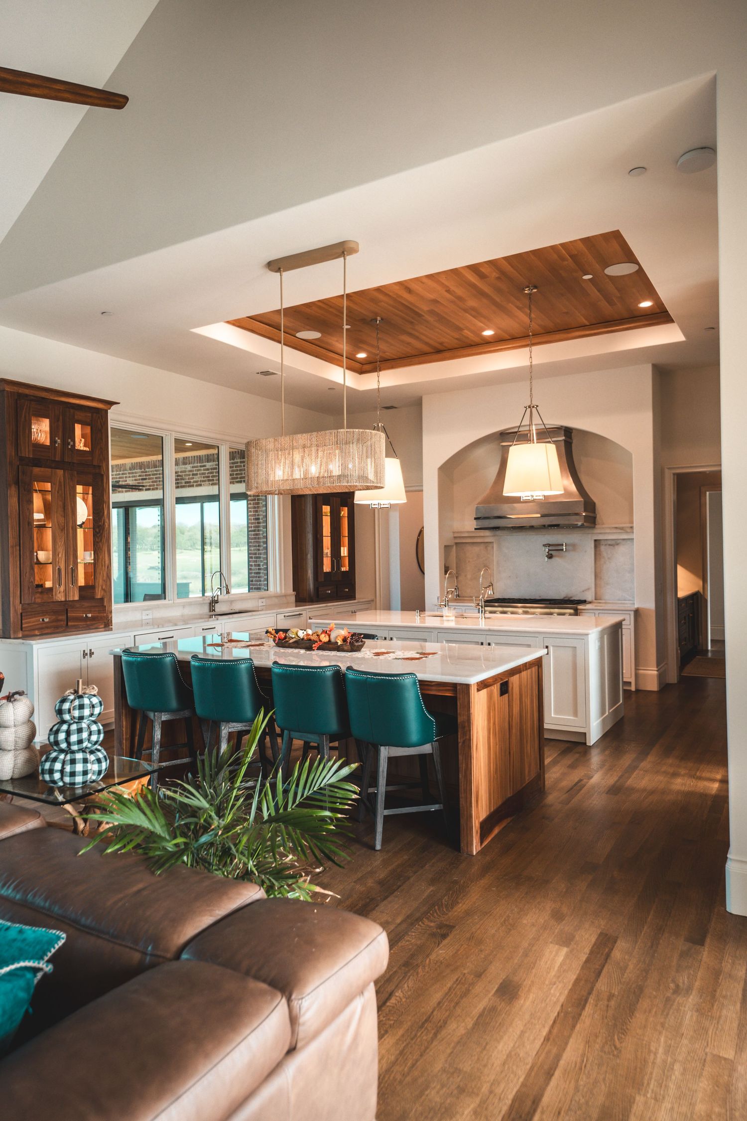 Open concept living area with hardwood floors, teal accents, and contemporary wood ceiling details.