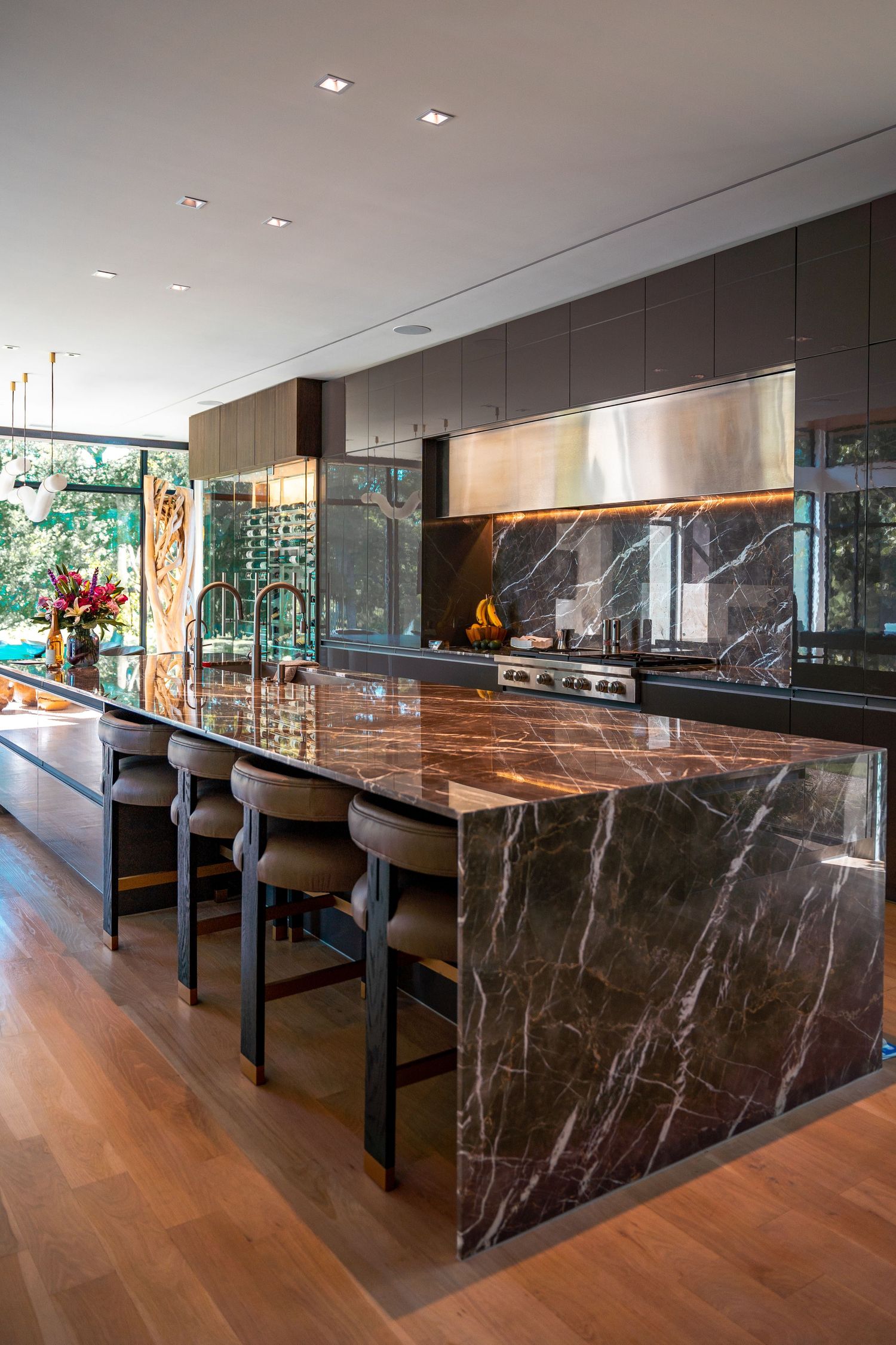 Elegant kitchen with dark marble countertops, hardwood flooring, and modern bar seating.