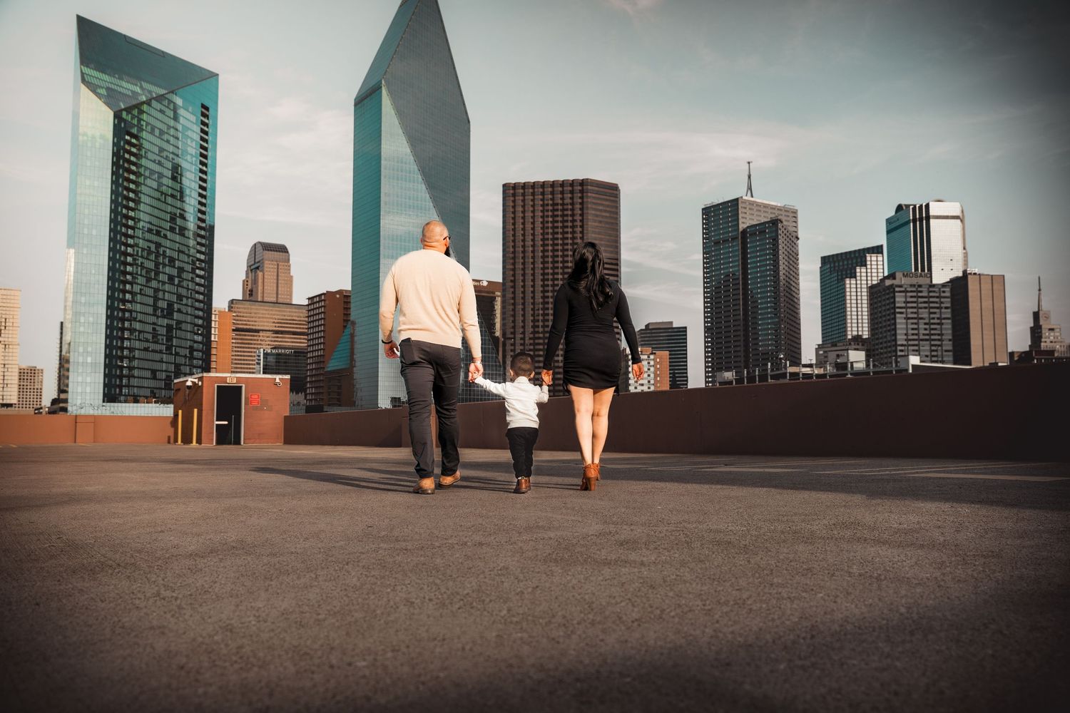 A couple stands against a city skyline backdrop during golden hour.