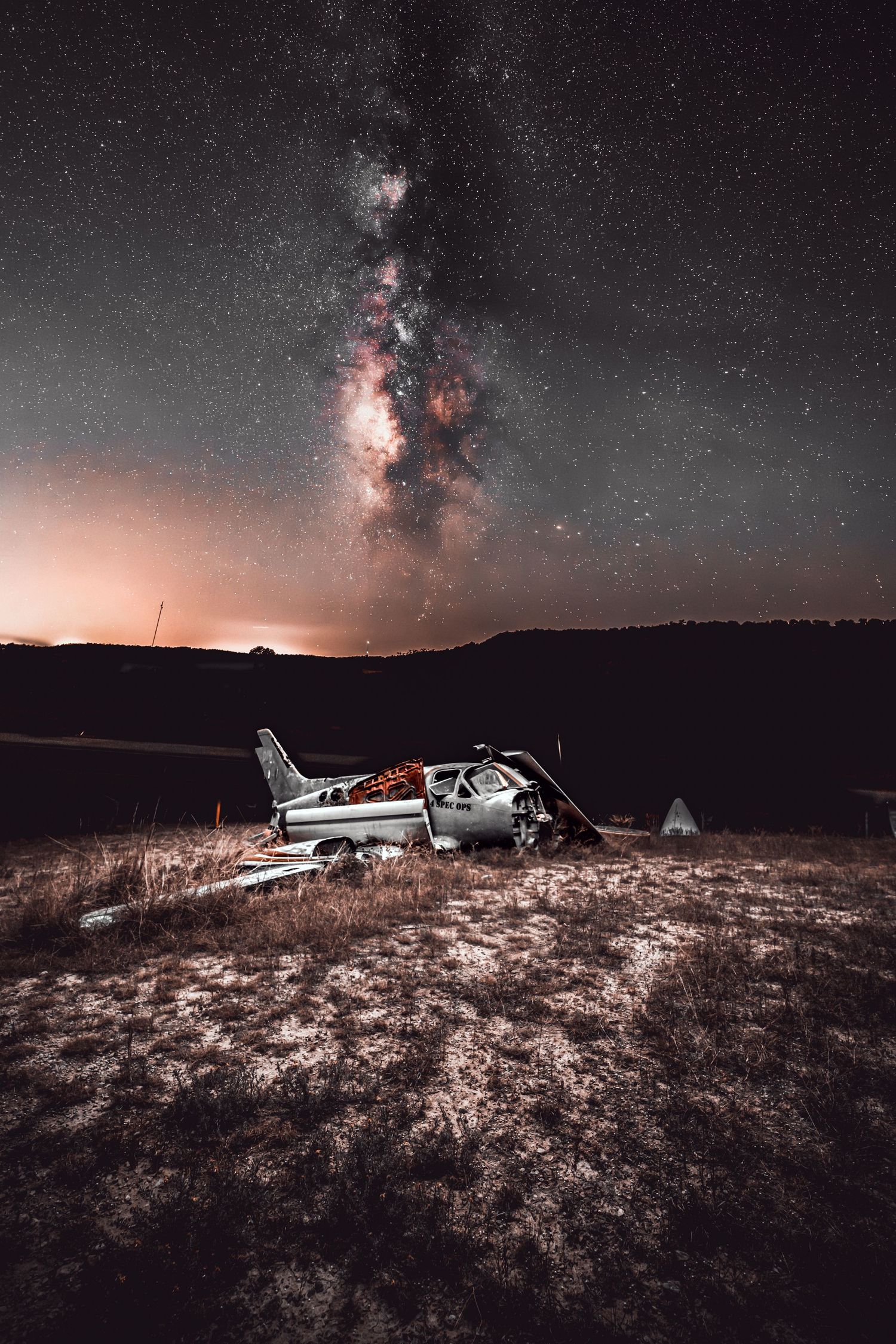 Abandoned airplane wreckage under a starry night sky with the Milky Way visible.