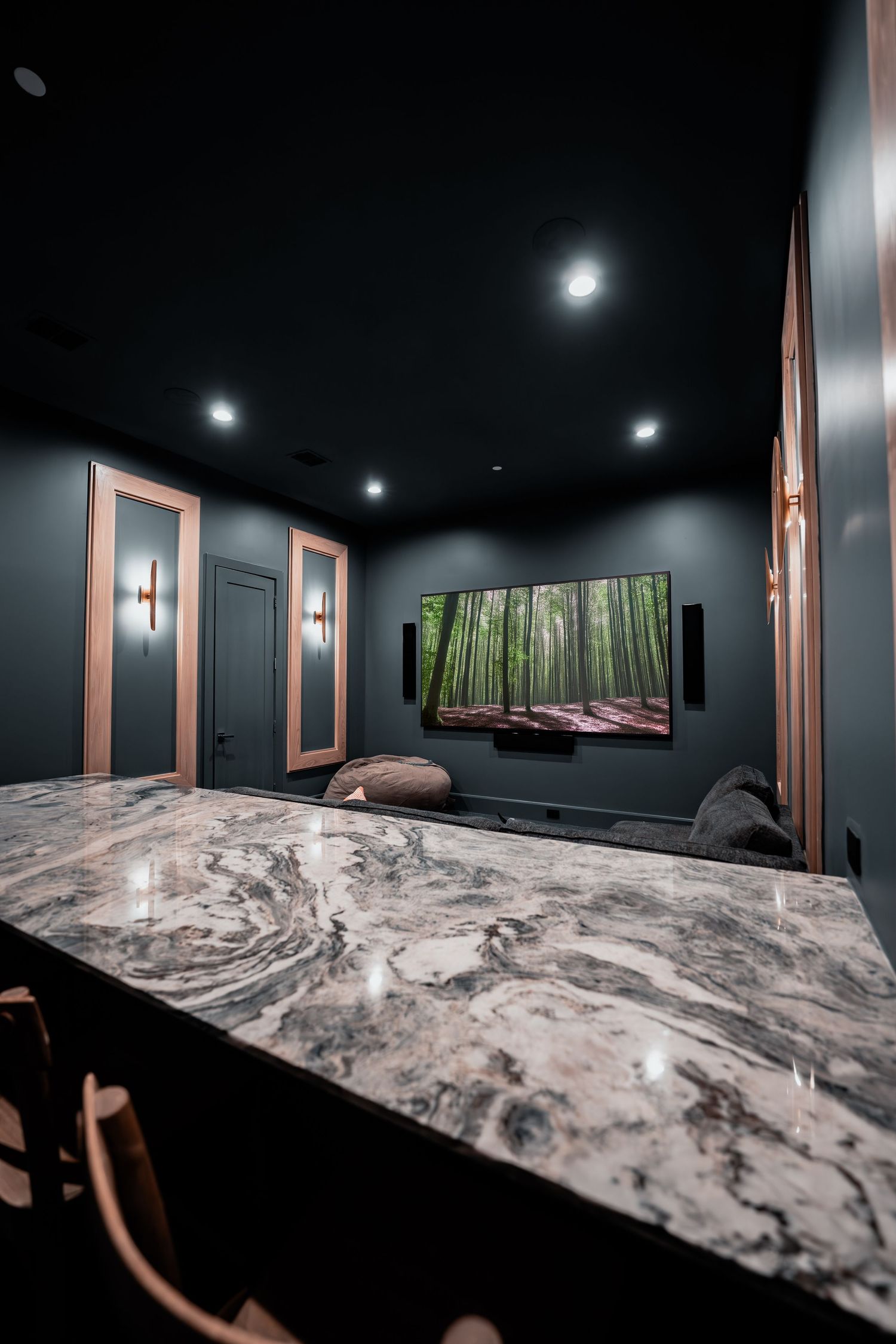 Dark moody entertainment room with dramatic marble countertops and ambient lighting.