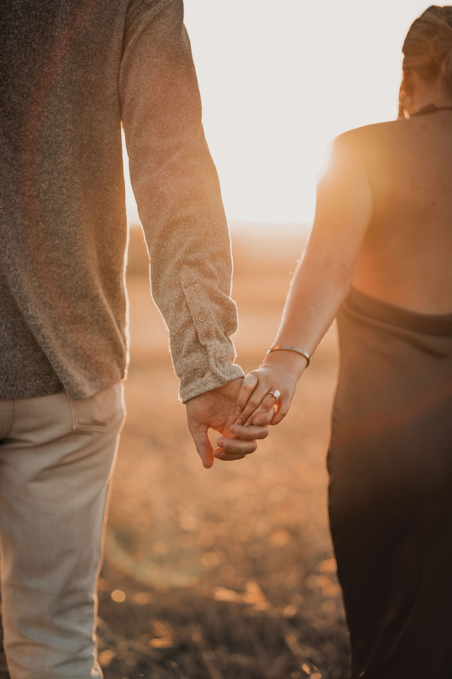 Close-up of couple holding hands during golden hour.