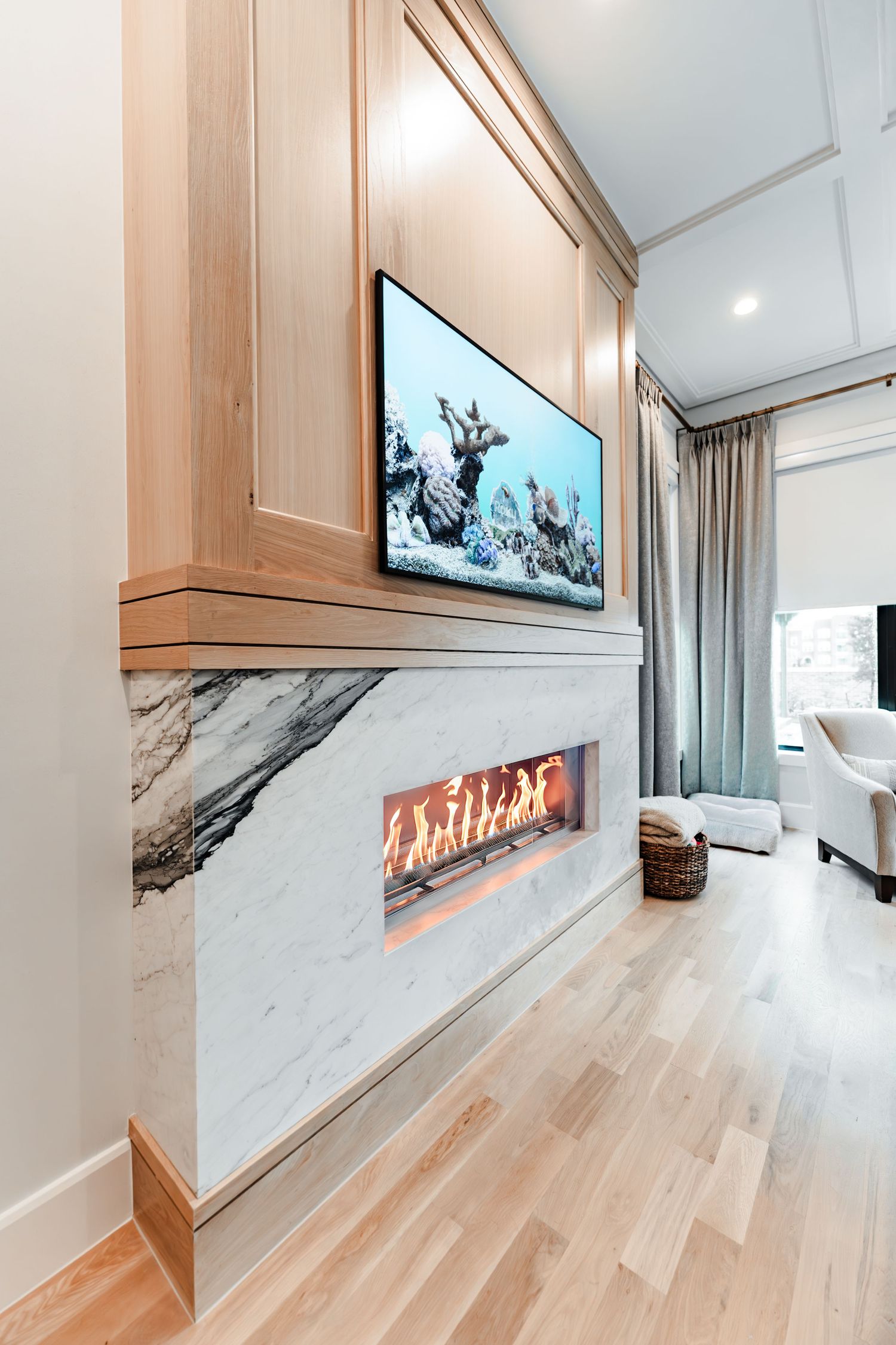 Modern living space with built-in fireplace, light wood flooring, and marble accent wall.