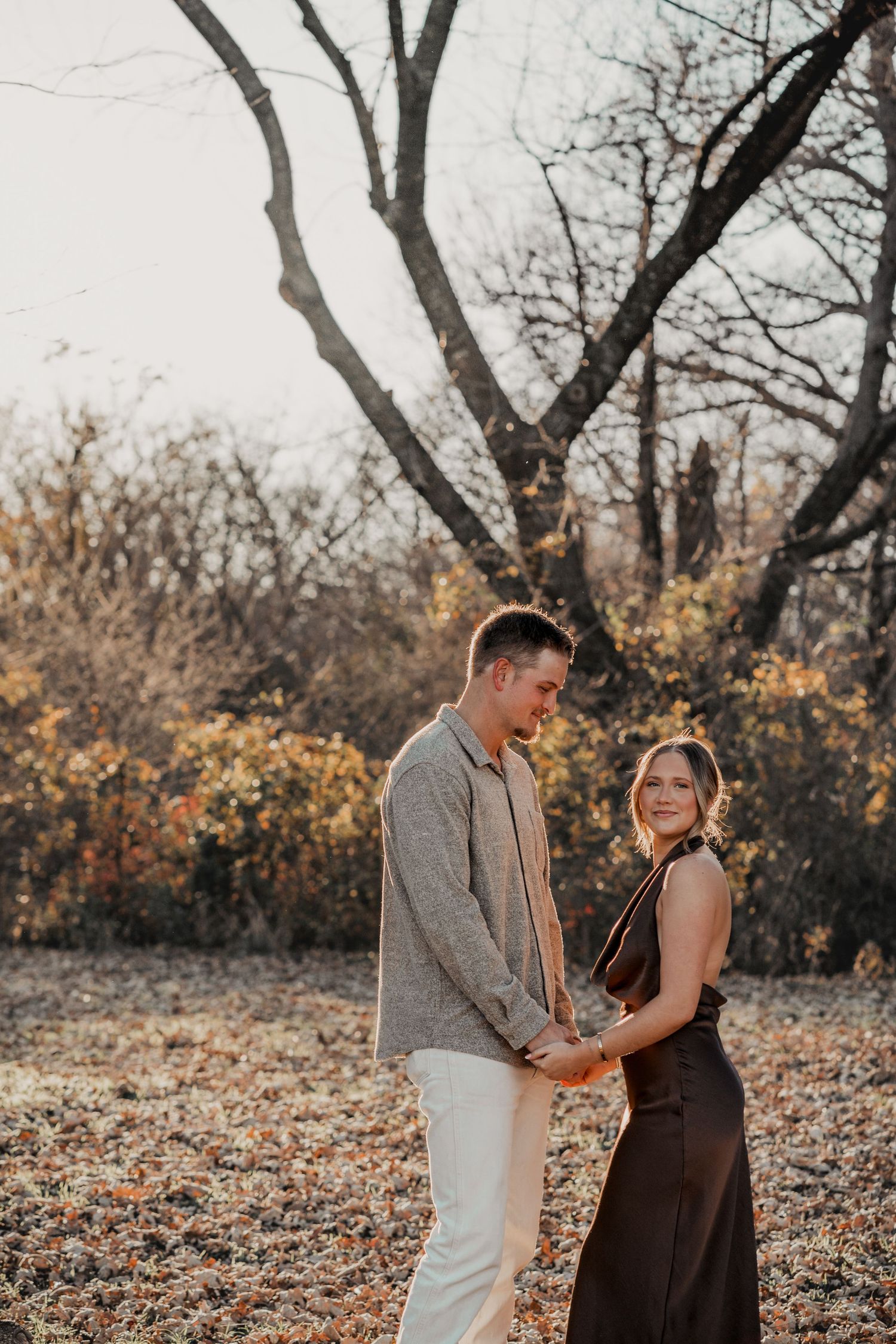 Couple sharing romantic moment among autumn trees at sunset.