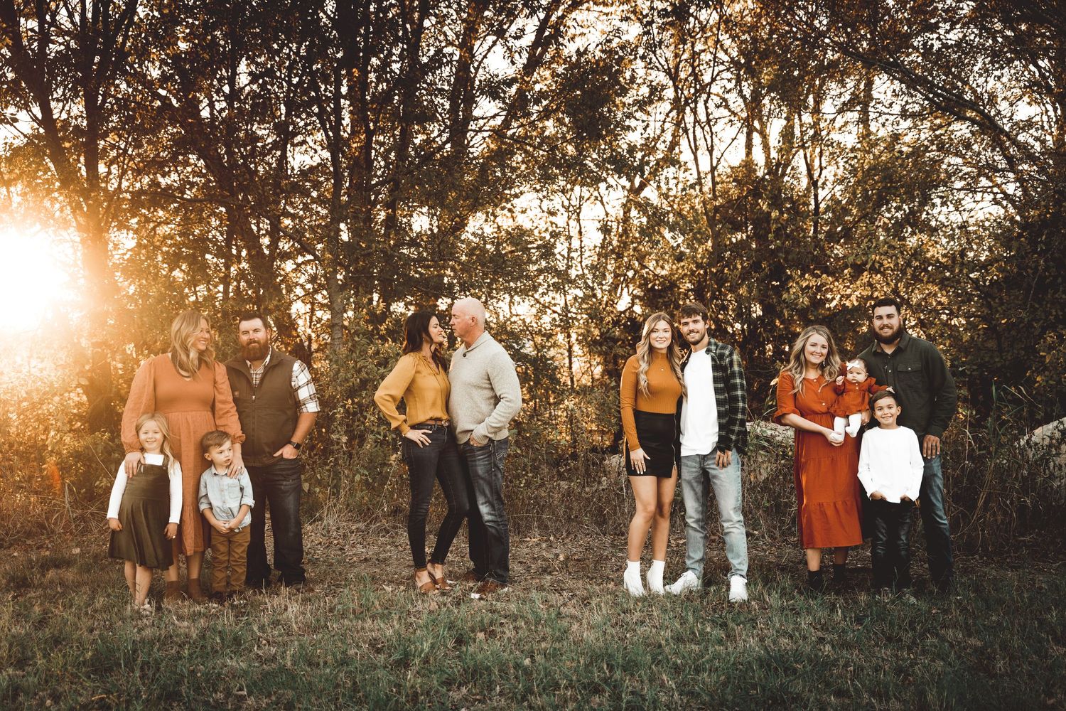 Large group portrait of people in casual attire standing together at sunset.