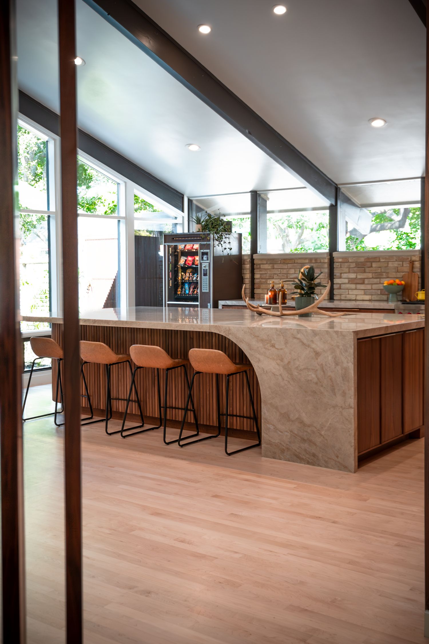 Bright open-concept space with marble island, wood accents, and contemporary bar seating.