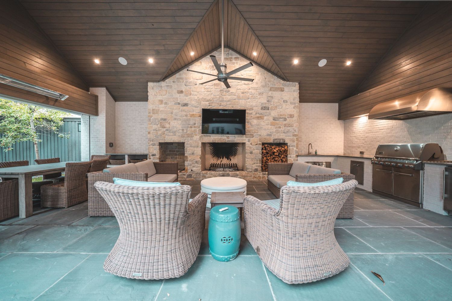 Modern outdoor living space with wicker furniture and wood plank ceiling.