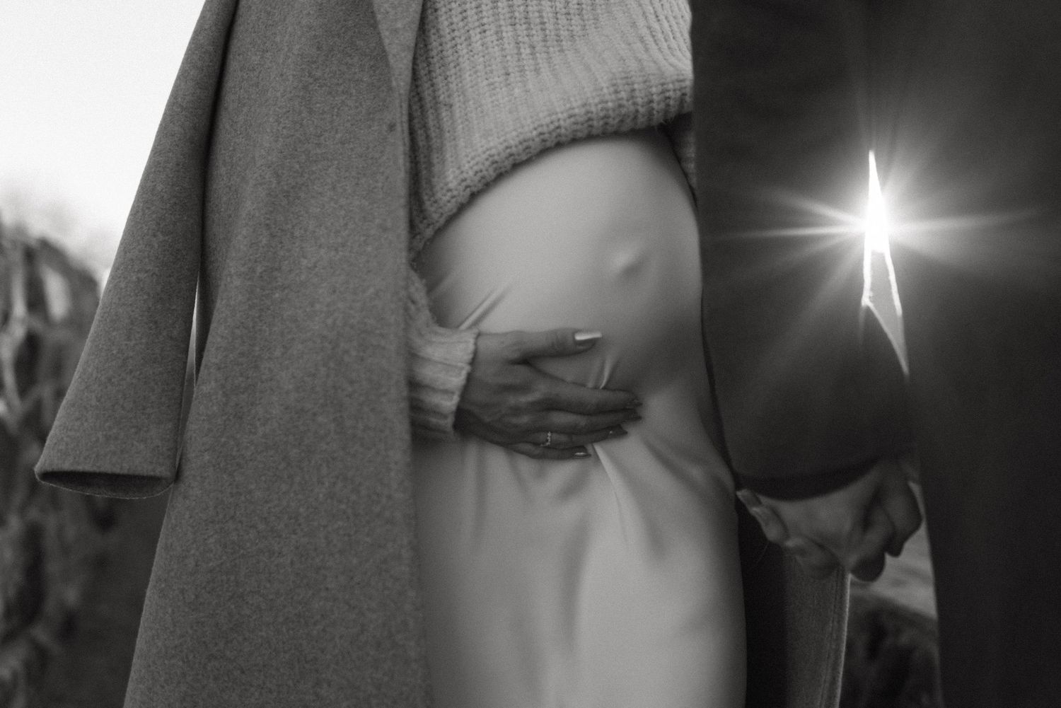 Baby bump, couple holding hands with a sun flare