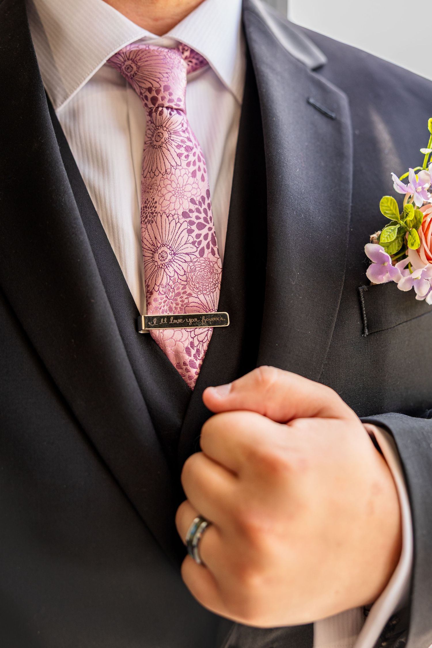 groom holding jacket for wedding photos highlighting groom's tie, ring, tie clip, and flowers for wedding day in Jefferson City, MO