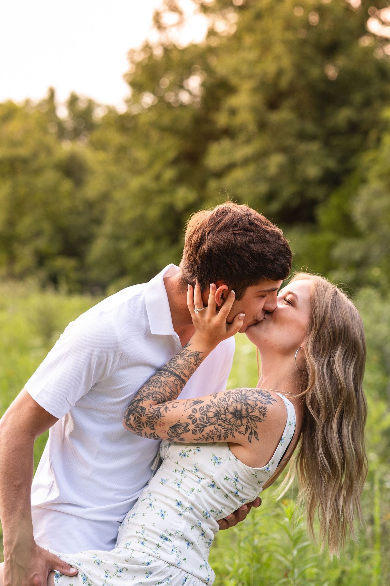 boy dipping girl and kissing her highlighting her engagement ring for engagement photos in field in Columbia Missouri