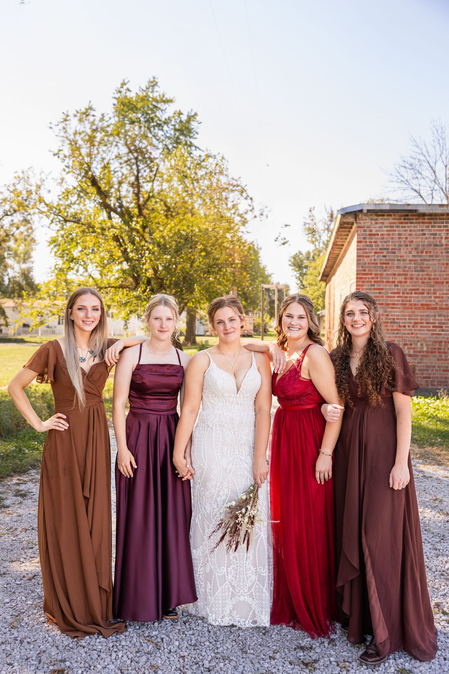bride and bridal party holding hands and smiling at the camera during wedding party photos for wedding photographer in Moberly MO