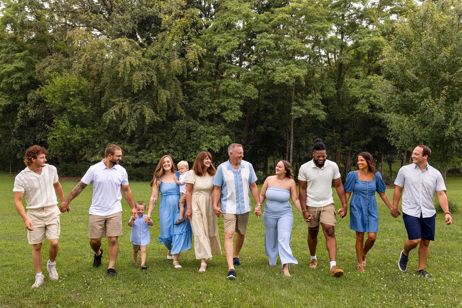 extended family photo session during summer portraits session at a park in Missouri, extended family members walking and smiling at together