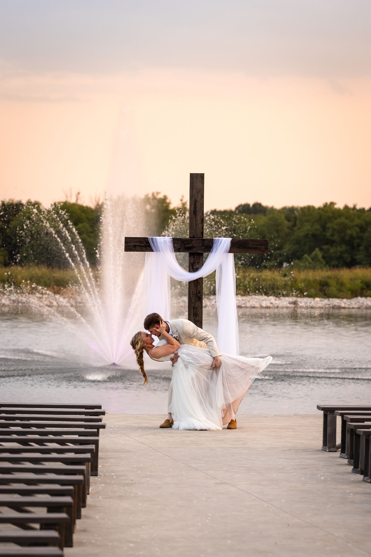 groom dipping bride in front of wedding altar for wedding portraits on wedding day in Boonville MO at sunset