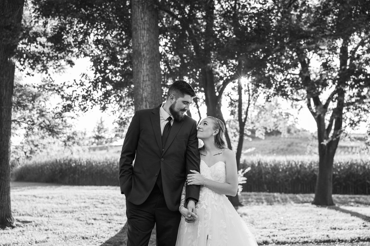 bride and groom standing next to each other holding hands smiling at each other for wedding photos during sunset on wedding day in KC MO